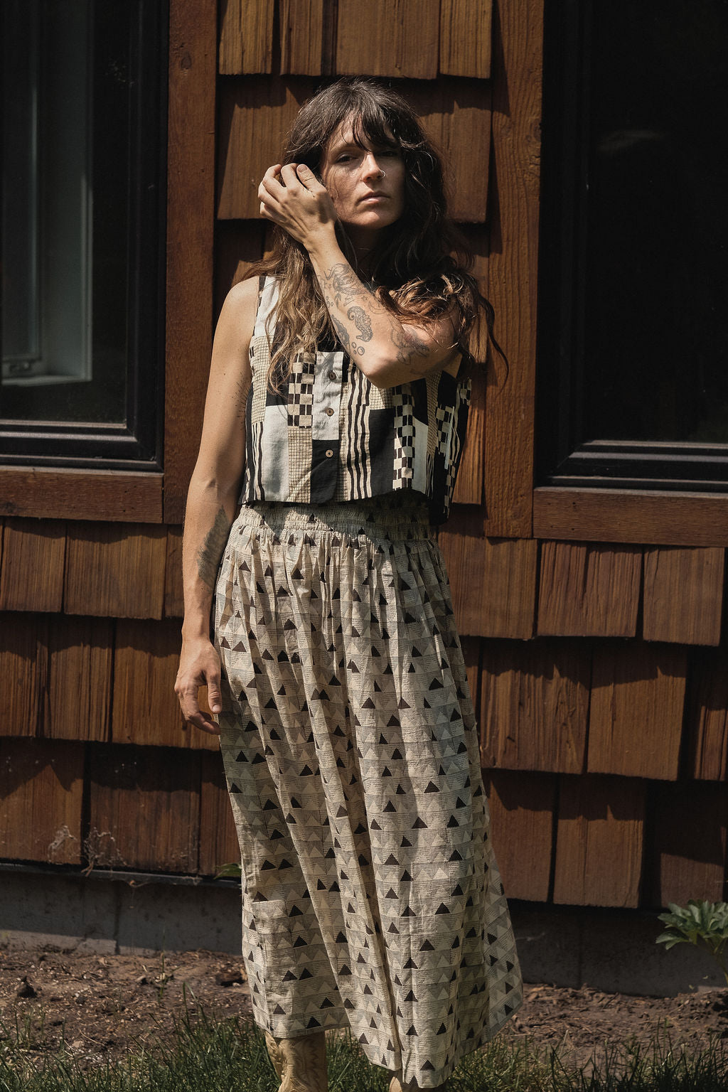 A mid-length, handwoven skirt made from soft, breathable organic cotton. The fabric features a delicate, all-over triangular block print in muted tones of black and grey on an off-white base. Lightly gathered at the waist, the skirt flows into a relaxed, voluminous silhouette that offers both comfort and movement. Naturally dyed and finished with a subtle texture, the skirt has an earthy, artisanal feel ideal for everyday wear.