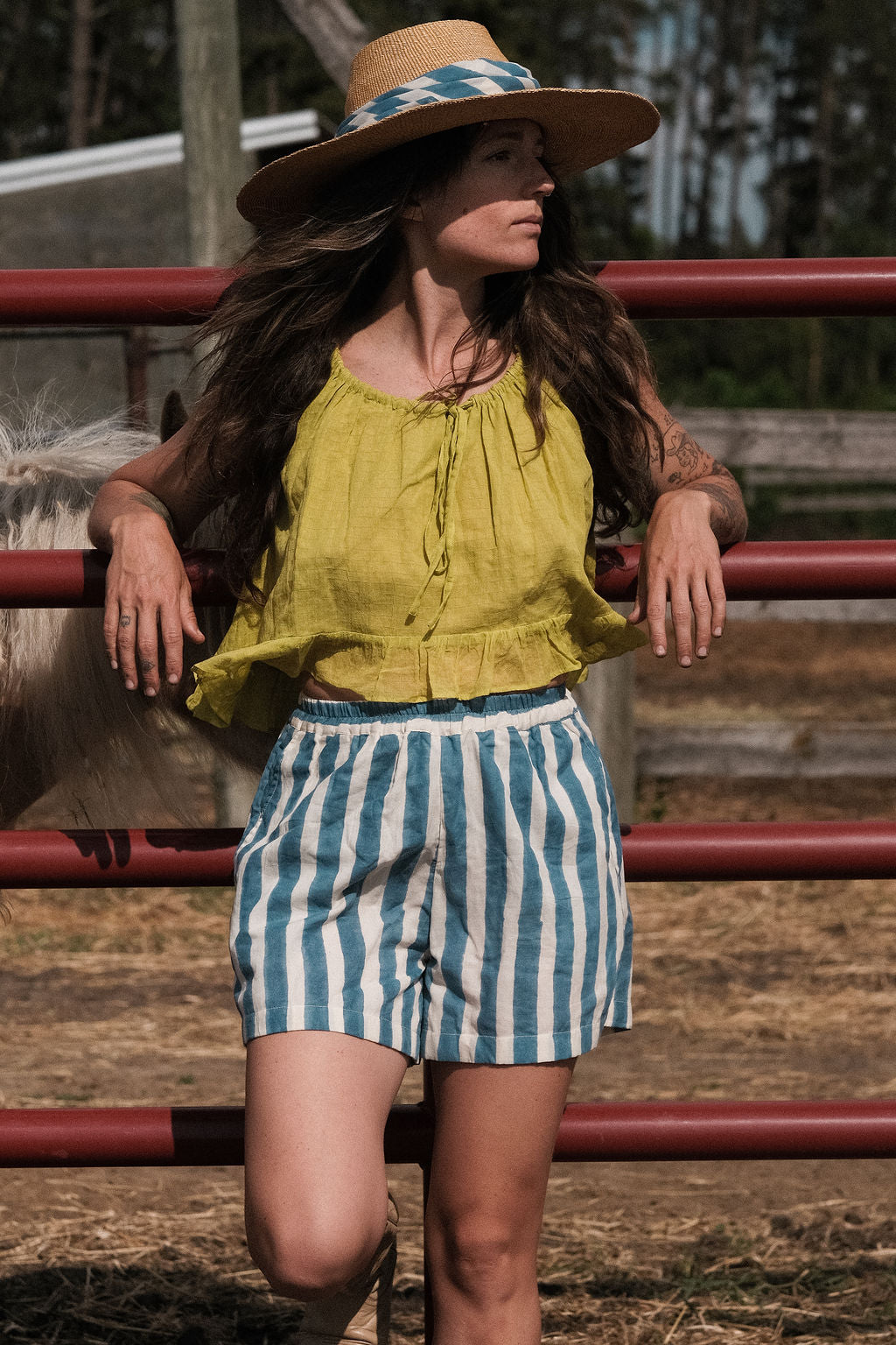 A sleeveless lime green top crafted from soft, handwoven organic cotton with a naturally crinkled texture. The fabric is naturally dyed using plant-based pigments, giving the lime tone a warm, earthy vibrance with subtle tonal variations. It features a gathered neckline with a fine tie detail at the front and a softly flared, cropped hem that creates an airy, relaxed silhouette ideal for summer.
