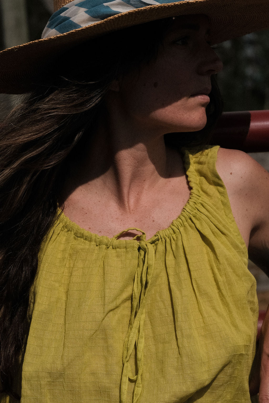 A sleeveless lime green top crafted from soft, handwoven organic cotton with a naturally crinkled texture. The fabric is naturally dyed using plant-based pigments, giving the lime tone a warm, earthy vibrance with subtle tonal variations. It features a gathered neckline with a fine tie detail at the front and a softly flared, cropped hem that creates an airy, relaxed silhouette ideal for summer.