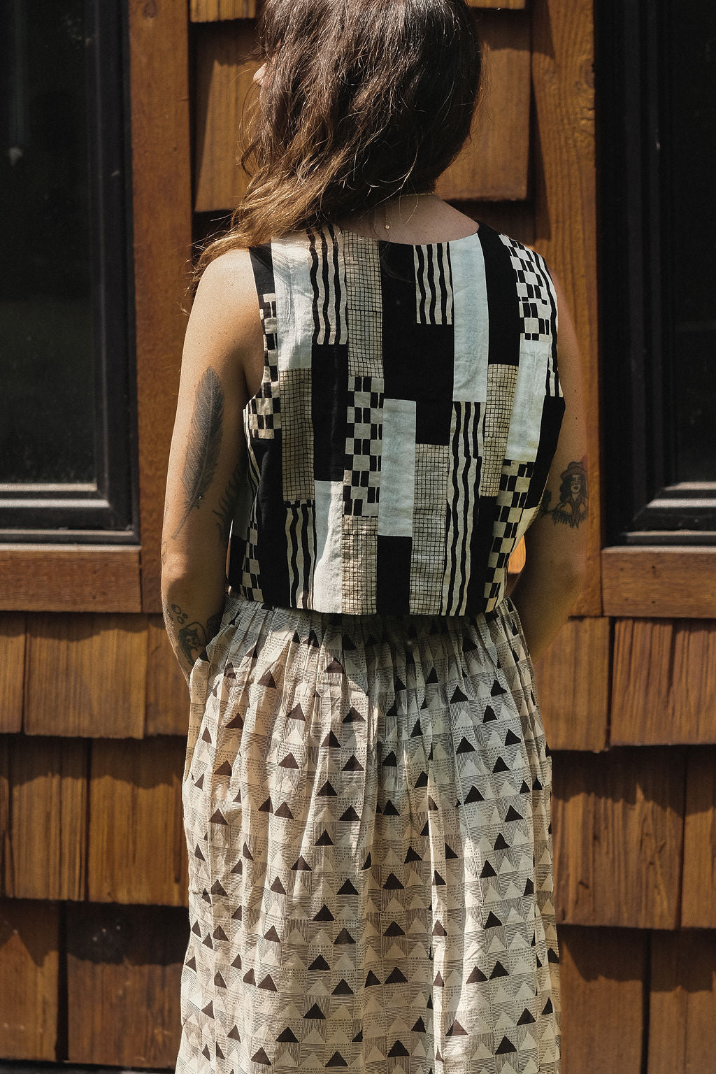 Sleeveless black and ivory patchwork top made from 100% organic cotton, featuring hand block-printed geometric patterns. Ethically crafted with a mix of stripes, checks, and textured prints using azo-free dyes. Lightweight, breathable fabric with a structured yet comfortable fit—perfect for summer styling or layering. Each piece is unique, showcasing subtle variations in print and color due to its handcrafted nature.