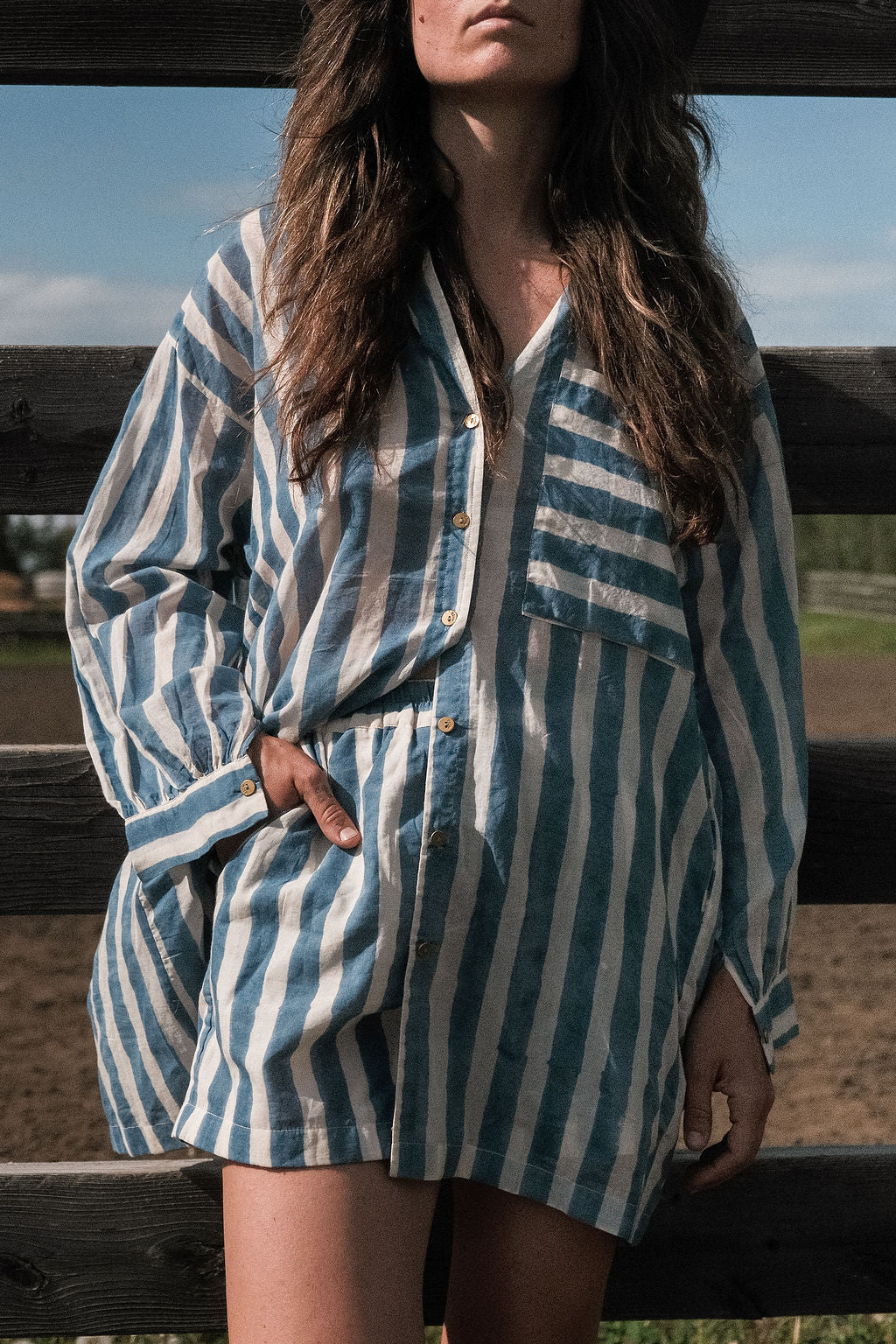This summer blue artist smock has vertical blue and white stripes, classic collar, and a chest pocket with contrasting horizontal stripes. Made with soft cotton fabric and natural color.  The coconut buttons add the charm to the shirt and ensure an easy enclosure.
