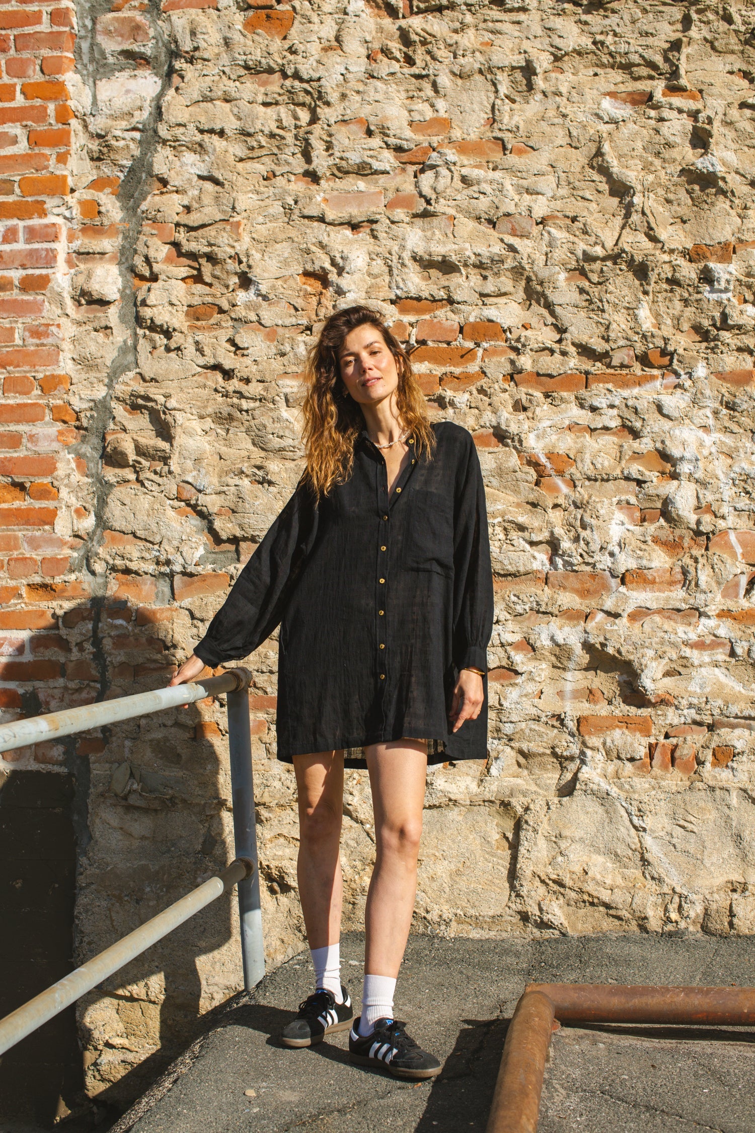 Black artist smock with a relaxed, oversized fit, featuring a button-down front, billowy long sleeves with gathered cuffs, and a subtle textured fabric. The lightweight, breathable material drapes effortlessly, creating a casual yet artistic look.