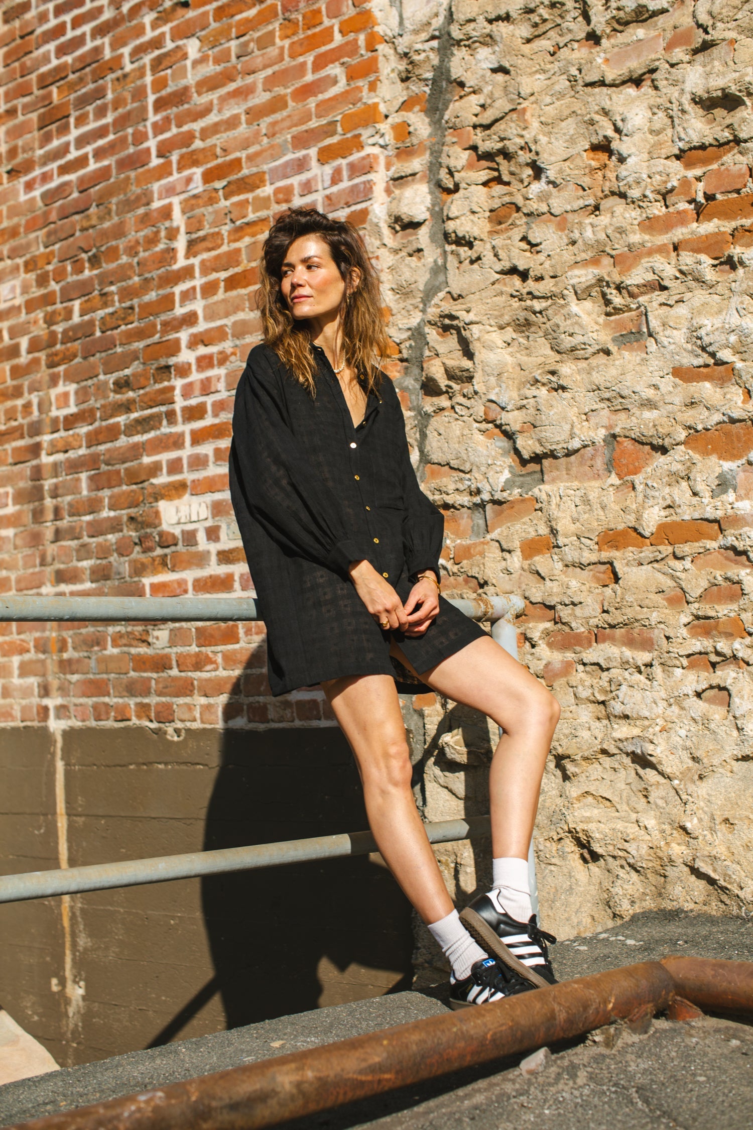 Black artist smock with a relaxed, oversized fit, featuring a button-down front, billowy long sleeves with gathered cuffs, and a subtle textured fabric. The lightweight, breathable material drapes effortlessly, creating a casual yet artistic look.