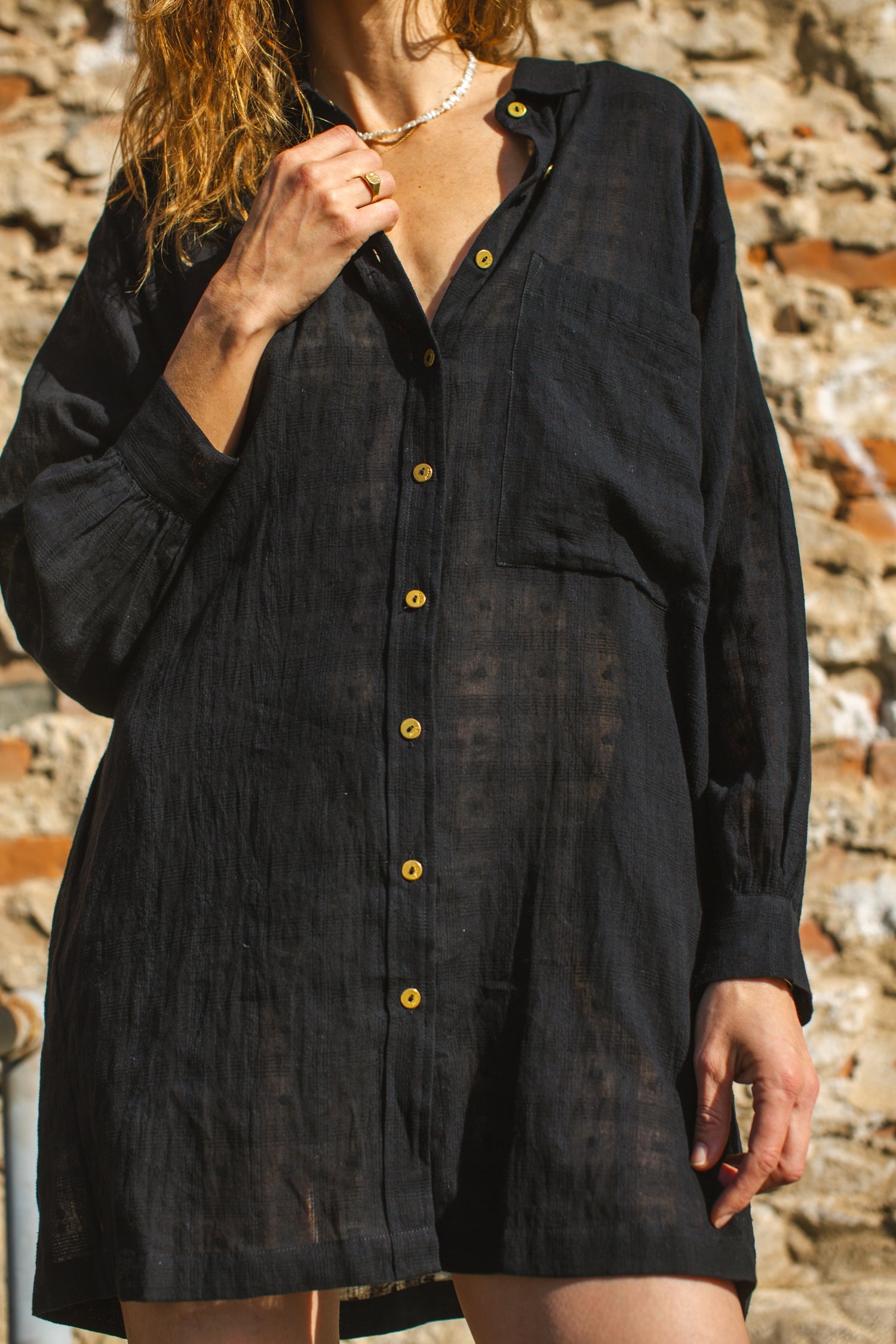 Black artist smock with a relaxed, oversized fit, featuring a button-down front, billowy long sleeves with gathered cuffs, and a subtle textured fabric. The lightweight, breathable material drapes effortlessly, creating a casual yet artistic look.