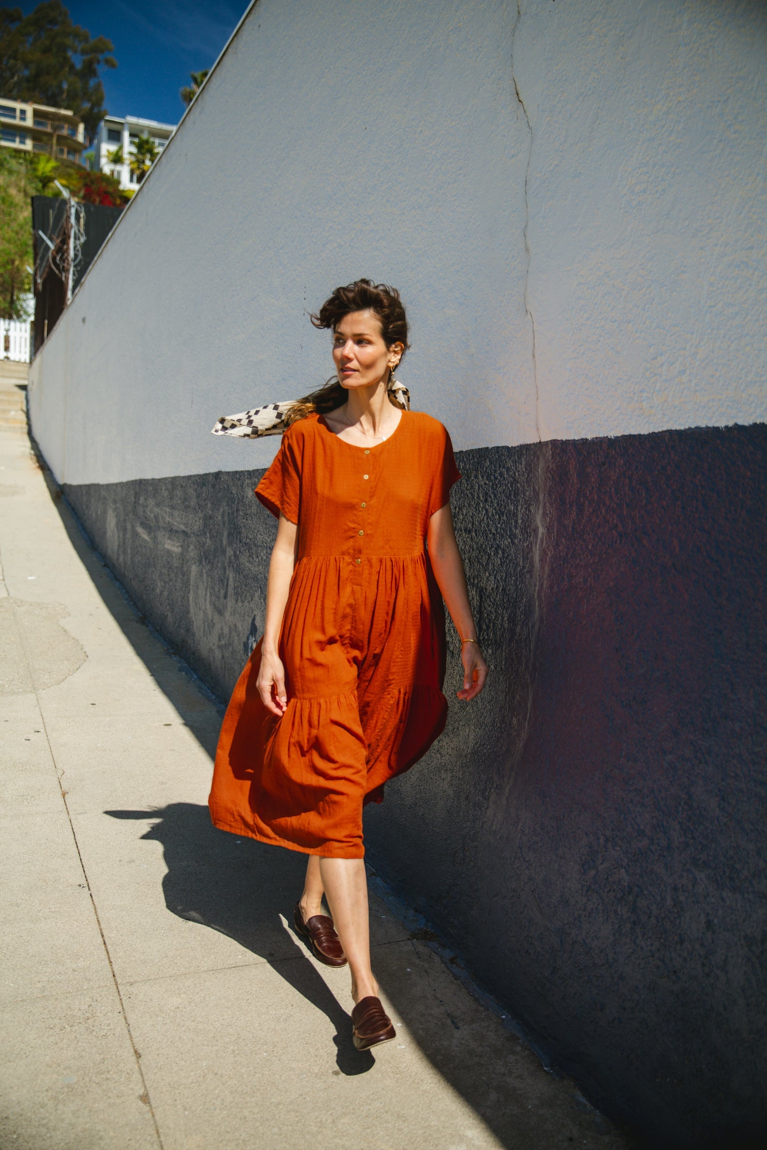 Rust orange tiered midi dress with a relaxed fit, short sleeves, a round neckline with a buttoned placket, and soft, lightweight fabric for an effortless, breezy style.