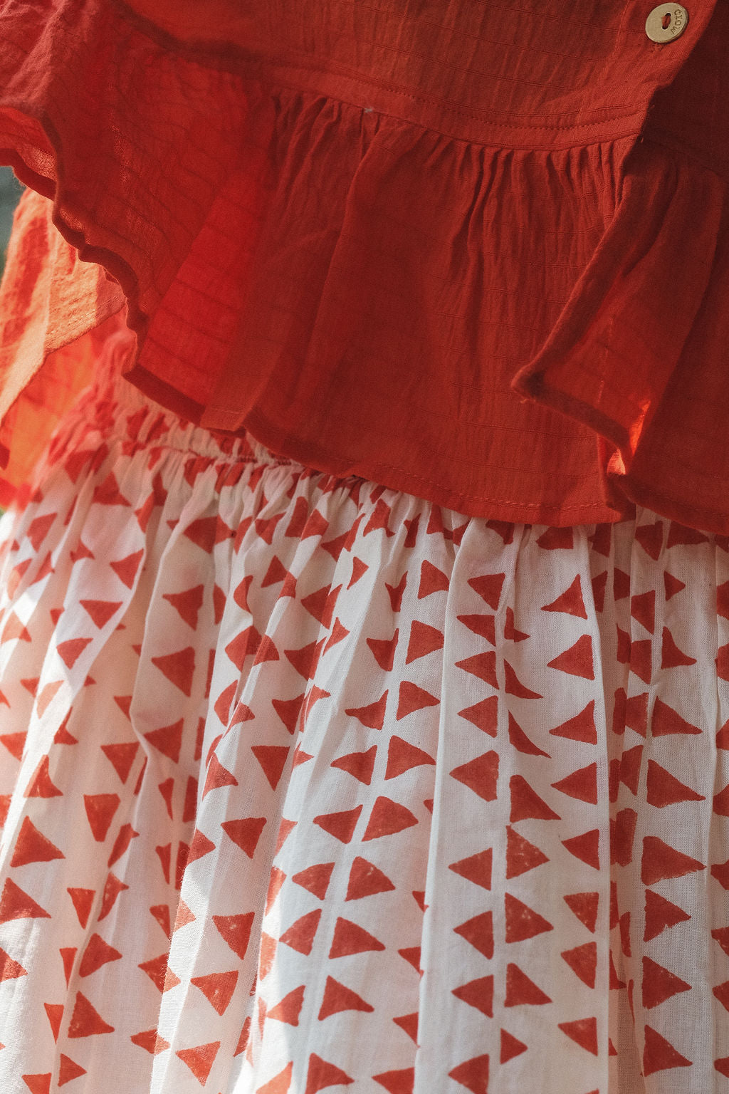 A vibrant red, cropped button-down top made from lightweight, handwoven organic cotton. The top features a relaxed fit with dropped shoulders and three-quarter sleeves, finished with a narrow cuff. The modern stan collar adds the charm to this lively top. The natural texture and breathable fabric give it an airy, effortless feel, ideal for warm-weather dressing.