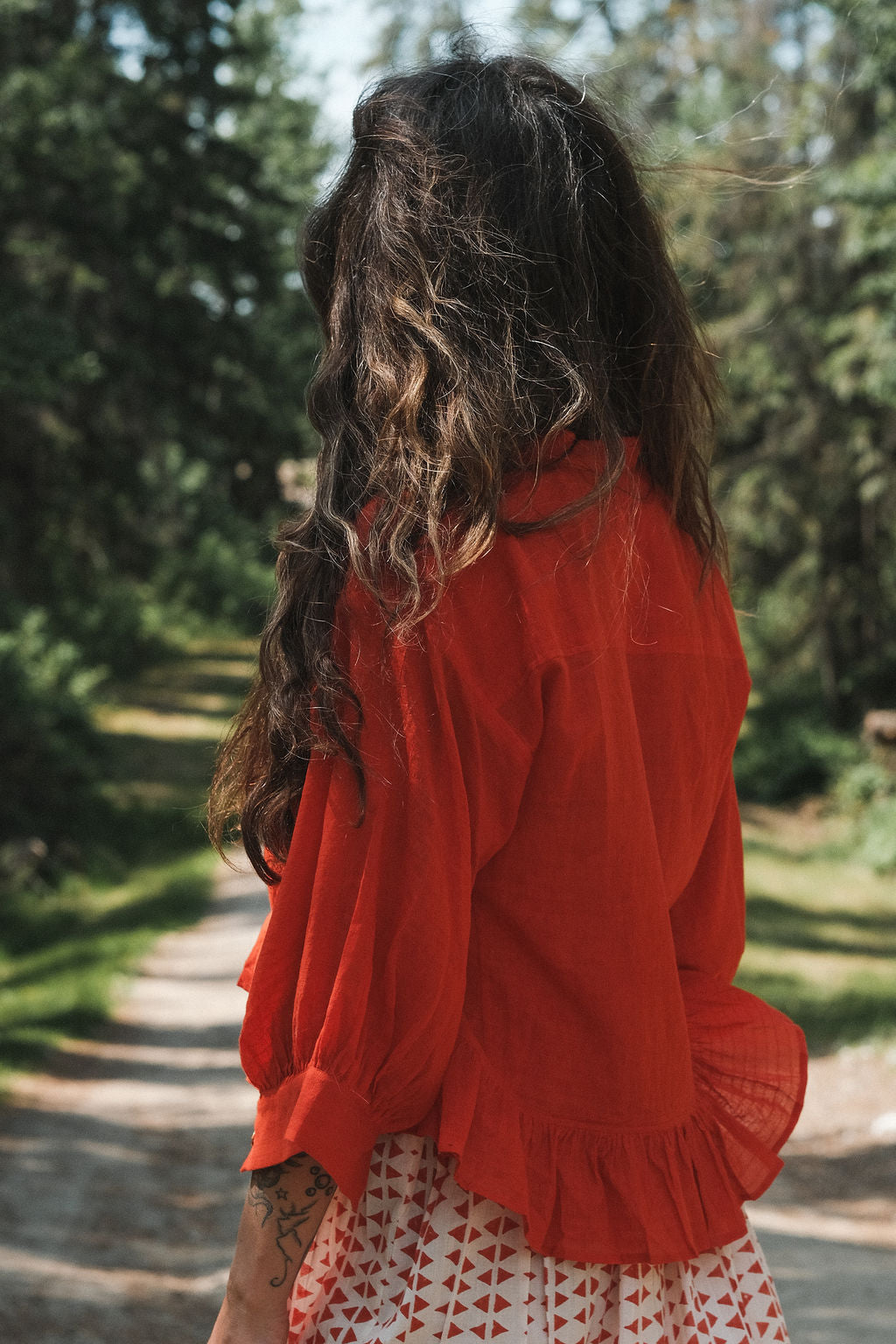 A vibrant red, cropped button-down top made from lightweight, handwoven organic cotton. The top features a relaxed fit with dropped shoulders and three-quarter sleeves, finished with a narrow cuff. The modern stan collar adds the charm to this lively top. The natural texture and breathable fabric give it an airy, effortless feel, ideal for warm-weather dressing.