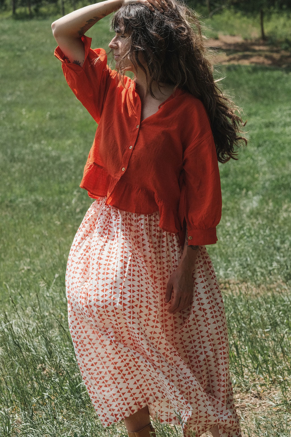 A vibrant red, cropped button-down top made from lightweight, handwoven organic cotton. The top features a relaxed fit with dropped shoulders and three-quarter sleeves, finished with a narrow cuff. The modern stan collar adds the charm to this lively top. The natural texture and breathable fabric give it an airy, effortless feel, ideal for warm-weather dressing.