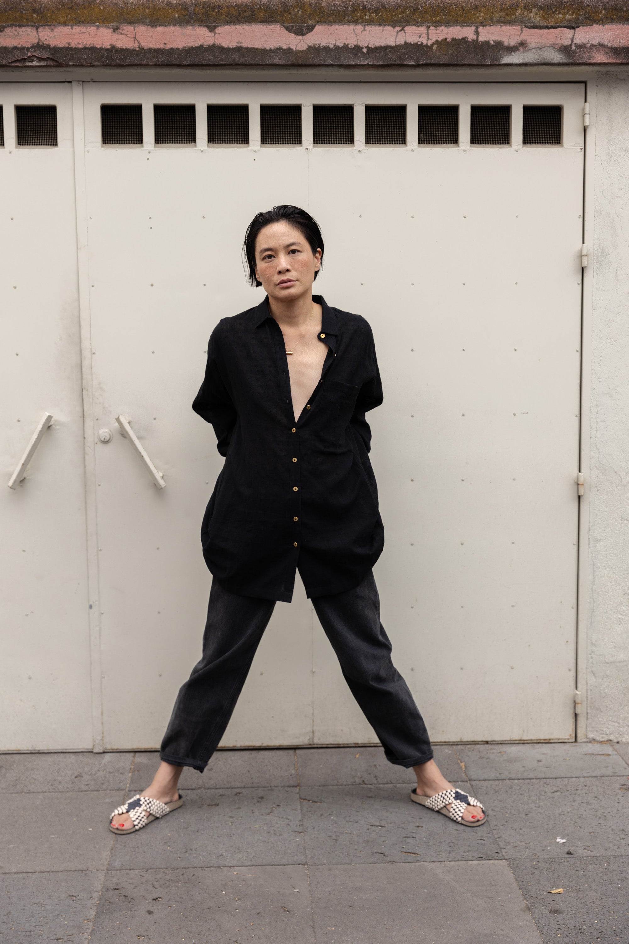 Black artist smock with a relaxed, oversized fit, featuring a button-down front, billowy long sleeves with gathered cuffs, and a subtle textured fabric. The lightweight, breathable material drapes effortlessly, creating a casual yet artistic look.