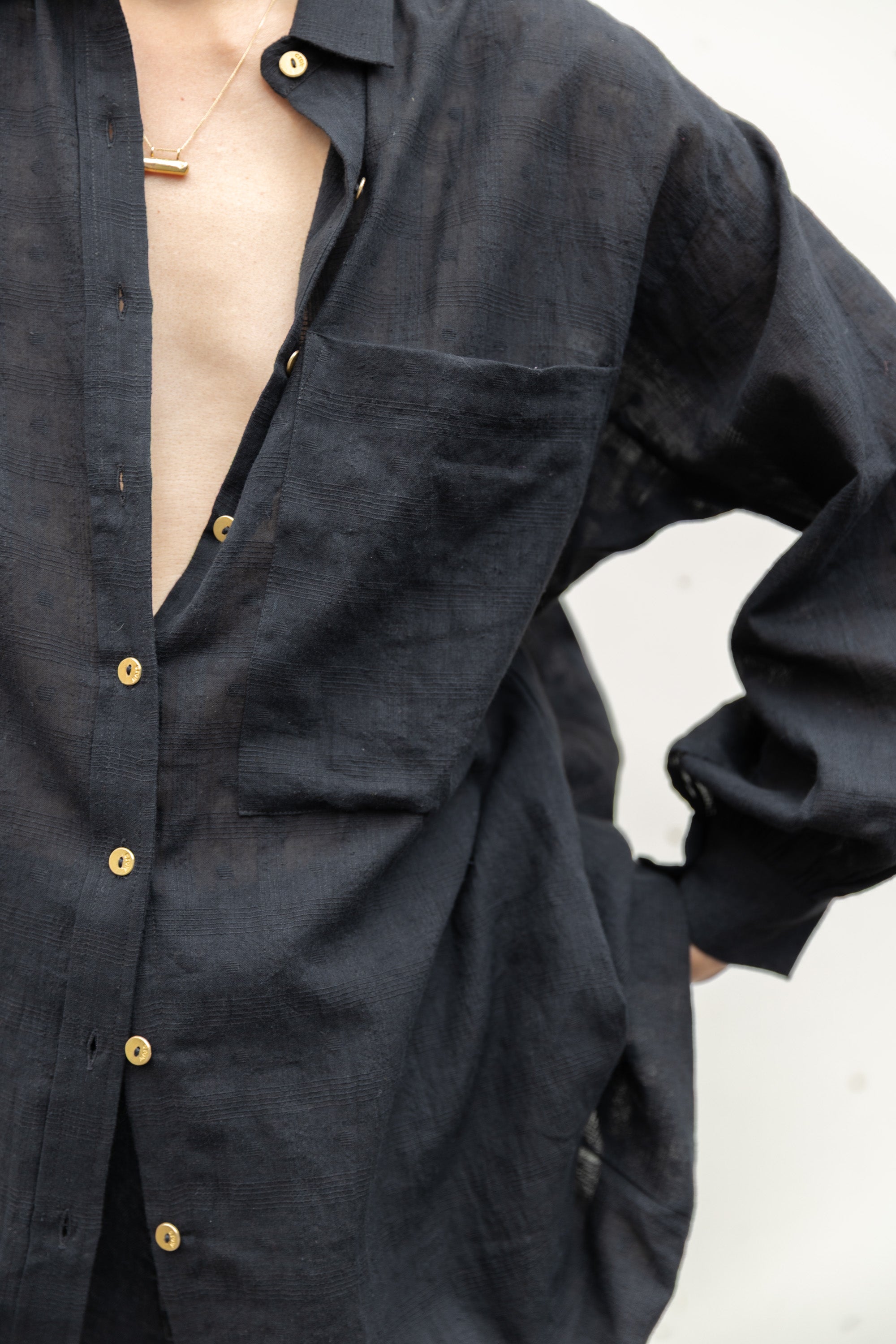 Black artist smock with a relaxed, oversized fit, featuring a button-down front, billowy long sleeves with gathered cuffs, and a subtle textured fabric. The lightweight, breathable material drapes effortlessly, creating a casual yet artistic look.