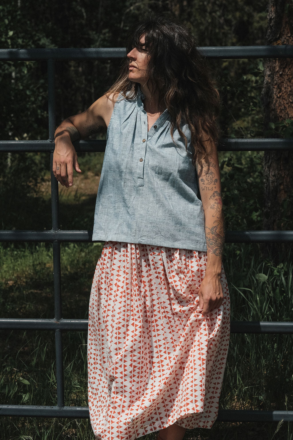 Sleeveless chambray blue top made from soft, handwoven organic cotton. Features a short button placket at the front and a subtle pleat detail below the collar, creating a clean and structured look. The stand collar adds a modern touch, while the breathable, lightweight fabric ensures comfort in warmer weather. Naturally dyed and ethically crafted, this top is perfect for effortless, everyday wear.