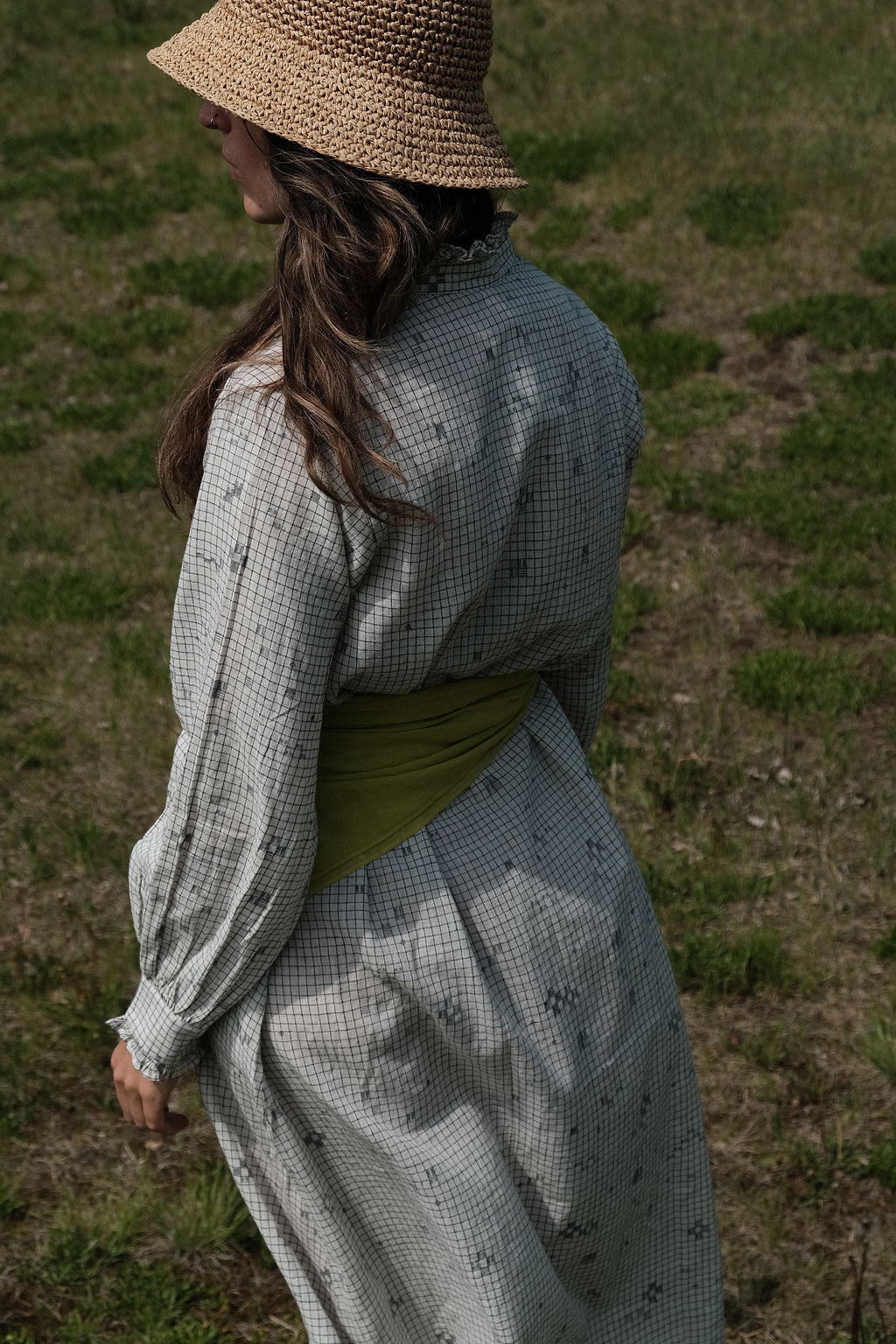 This Jamdani dress made with handwoven cotton is a perfect summer dress with its light color detailed square black threads. It has long sleeves with ruffles along a ruffled neck, and a midi length.