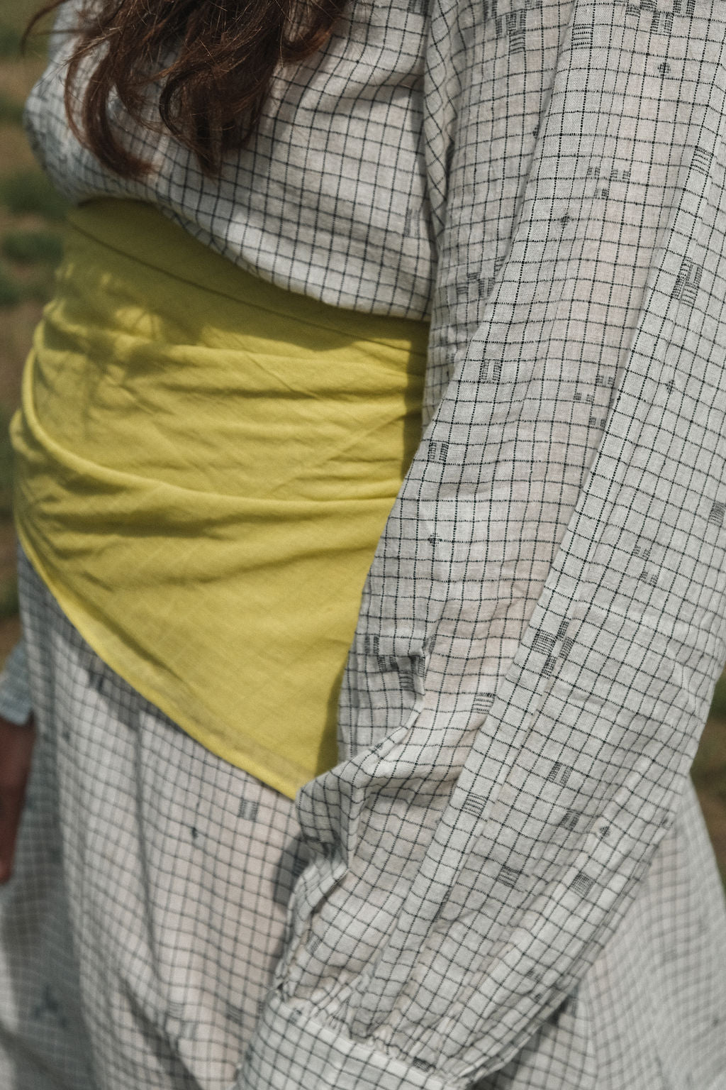This Jamdani dress made with handwoven cotton is a perfect summer dress with its light color detailed square black threads. It has long sleeves with ruffles along a ruffled neck, and a midi length.