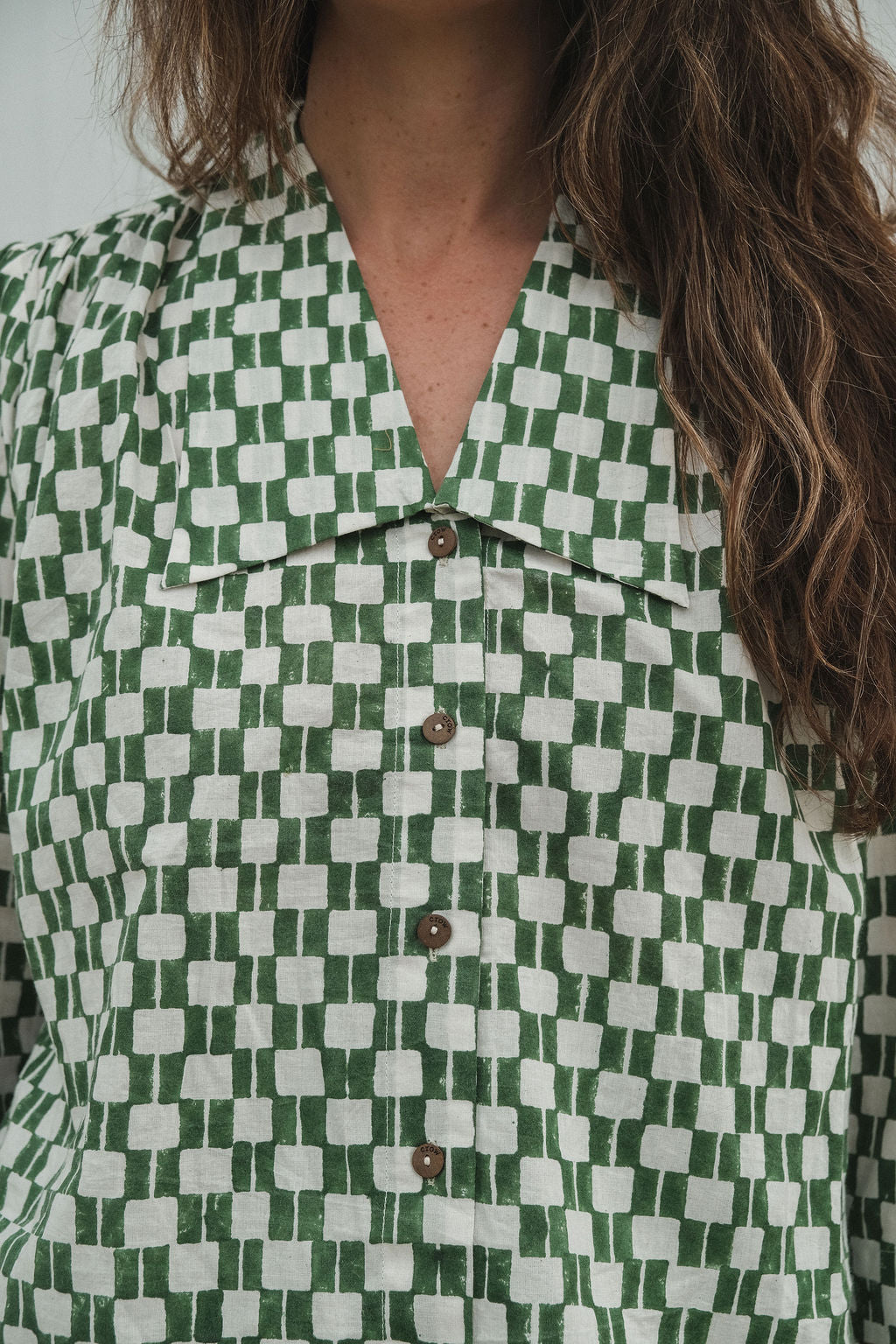 Green and white hand block-printed top made from 100% organic cotton, featuring a front button opening and a soft, breathable feel. Crafted using azo-free dyes and ethically produced, this lightweight, non-stretchy top falls 25” from the shoulder and offers a true-to-size fit. Each garment is uniquely one-of-a-kind, with natural variations in print and color that reflect its handcrafted origin—perfect for sustainable, everyday wear.