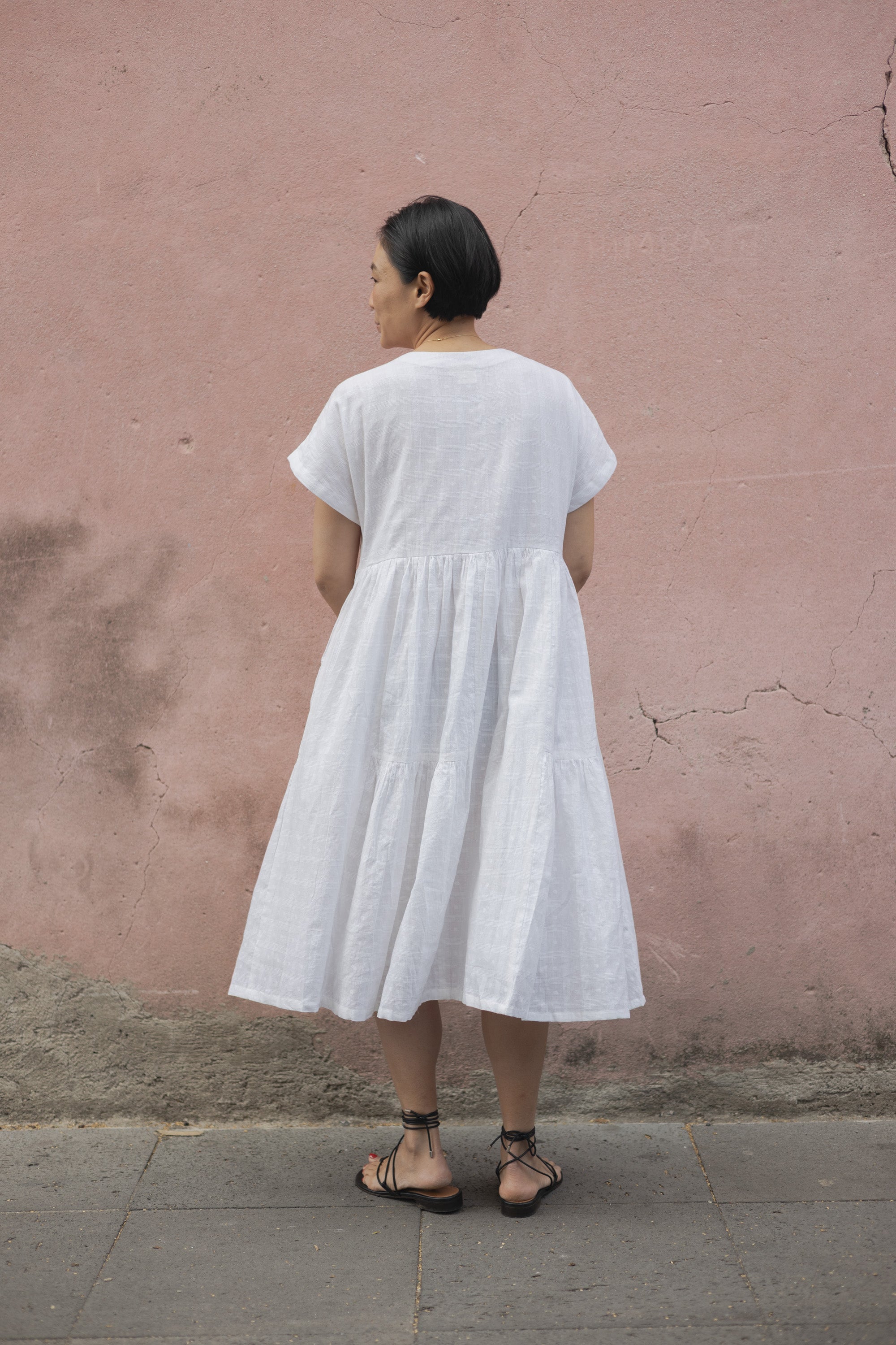 White A-line midi dress with cap sleeves, a button-down front, a gathered waist, it has delicate checks adding a texture to the garment. Made from lightweight, breathable fabric for a relaxed fit.