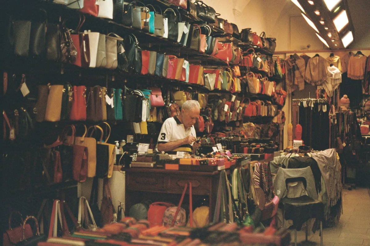 A craftsman at work in a shop full of leather bags