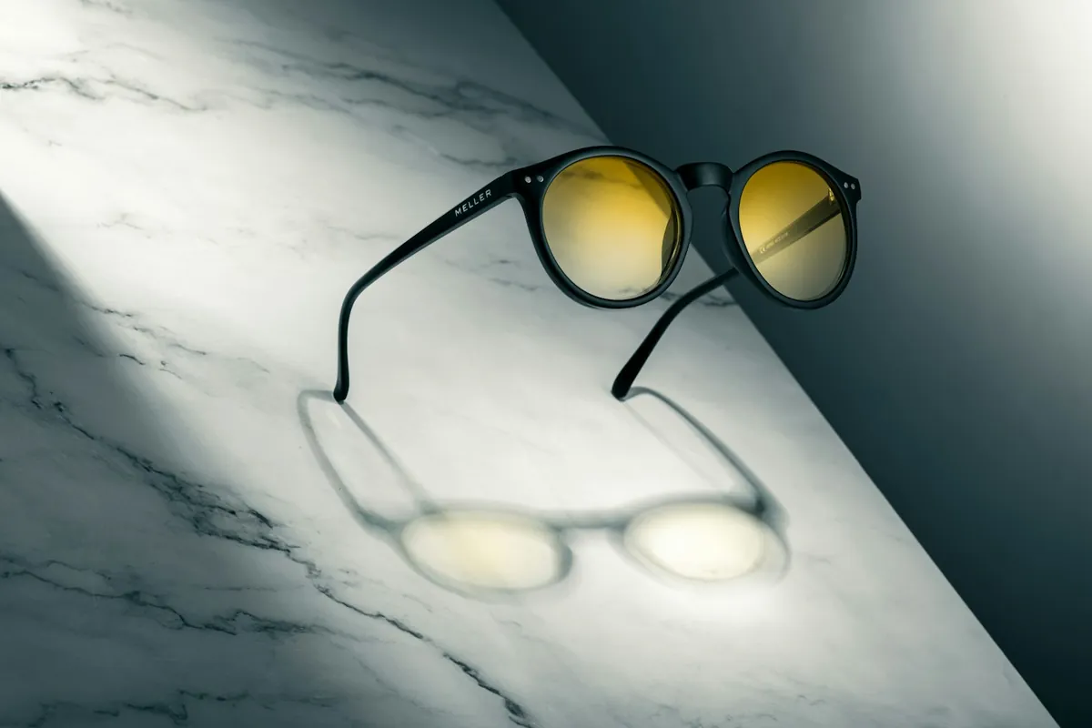 Sunglasses casting a shadow on white marble
