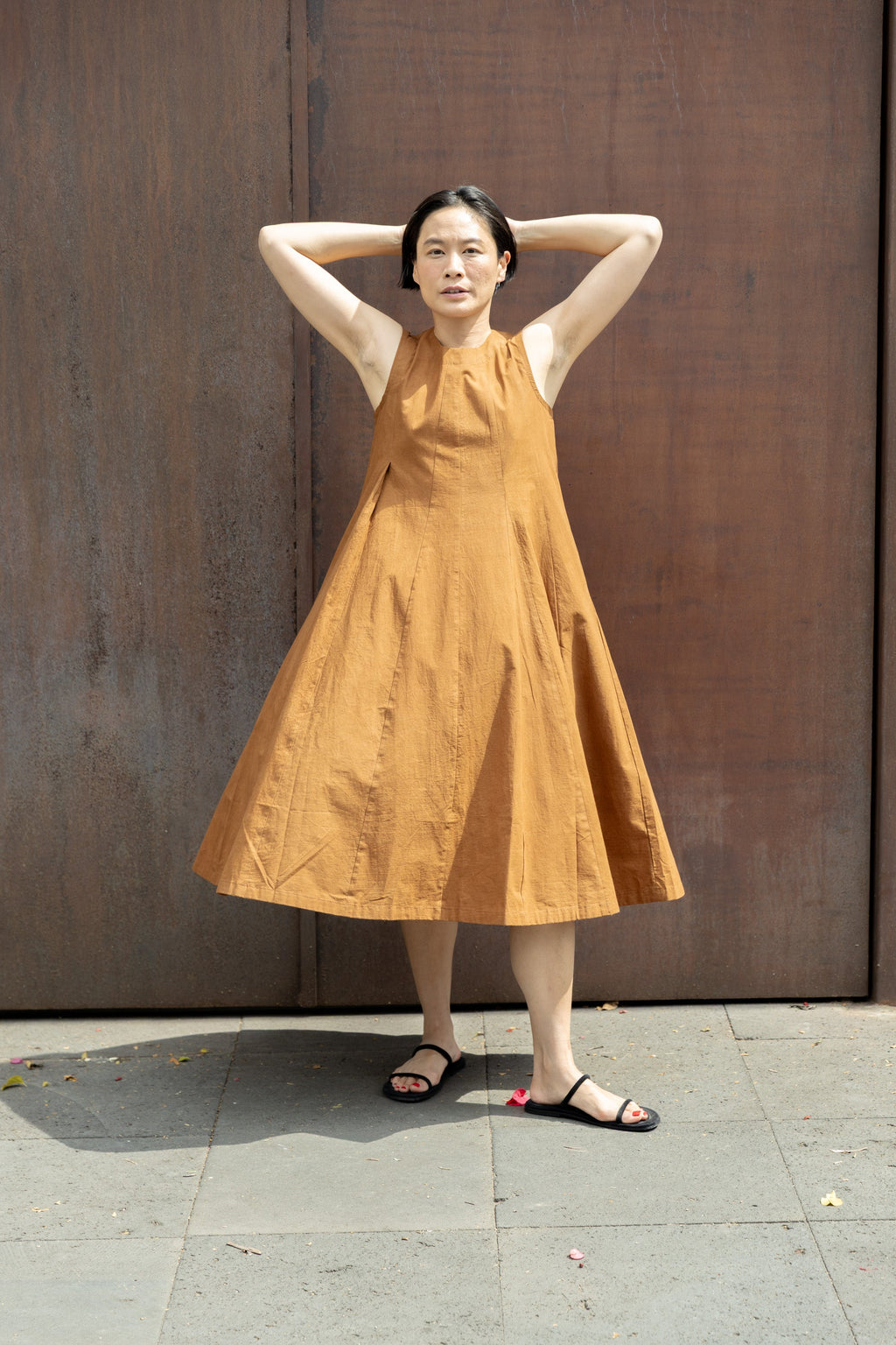 Sleeveless caramel-brown A-line midi dress with a high, round neckline. Features a voluminous flared silhouette, creating a breezy and effortless look. Made from textured, lightweight fabric for a natural, flowy drape.