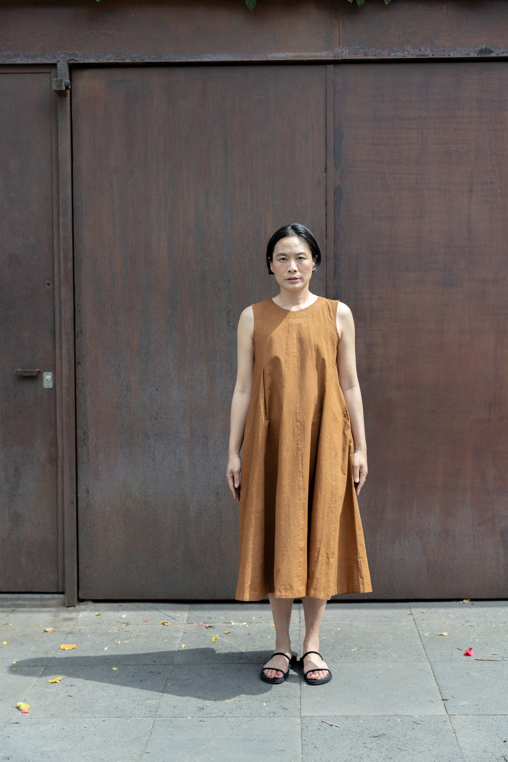 Sleeveless caramel-brown A-line midi dress with a high, round neckline. Features a voluminous flared silhouette, creating a breezy and effortless look. Made from textured, lightweight fabric for a natural, flowy drape.