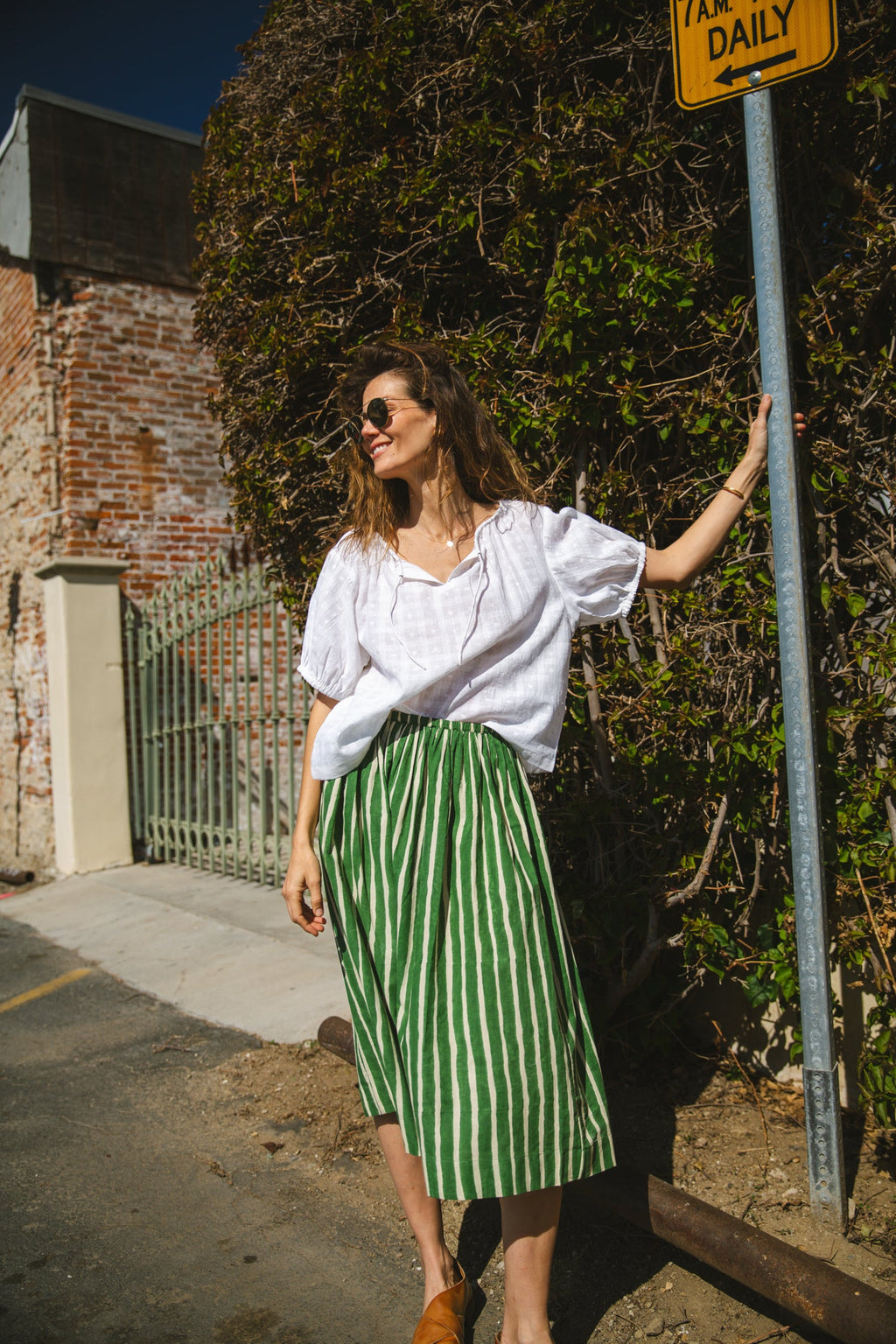 Green and white striped midi skirt with an elastic waistband, lightweight breathable fabric, and a gathered silhouette for a relaxed and stylish look.