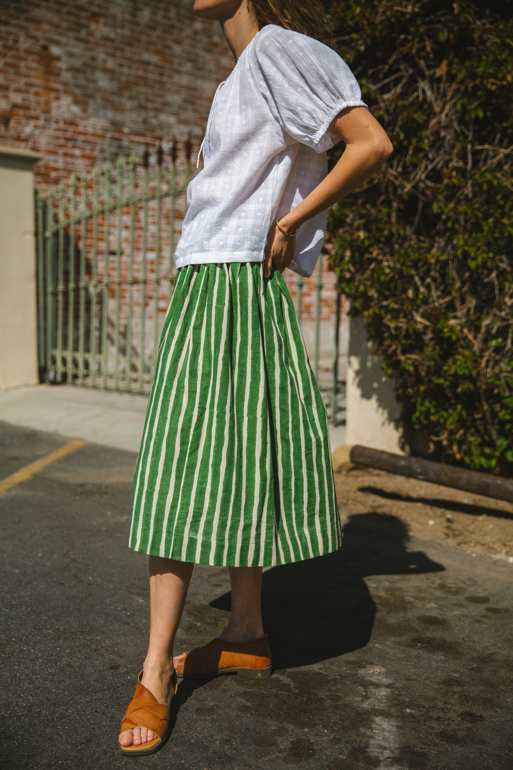 Green and white striped midi skirt with an elastic waistband, lightweight breathable fabric, and a gathered silhouette for a relaxed and stylish look.