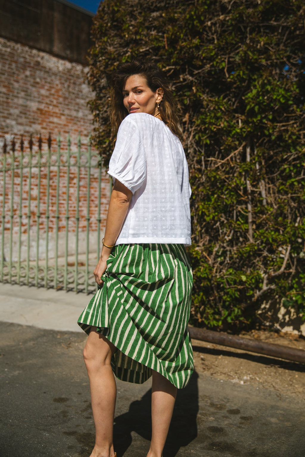 Green and white striped midi skirt with an elastic waistband, lightweight breathable fabric, and a gathered silhouette for a relaxed and stylish look.