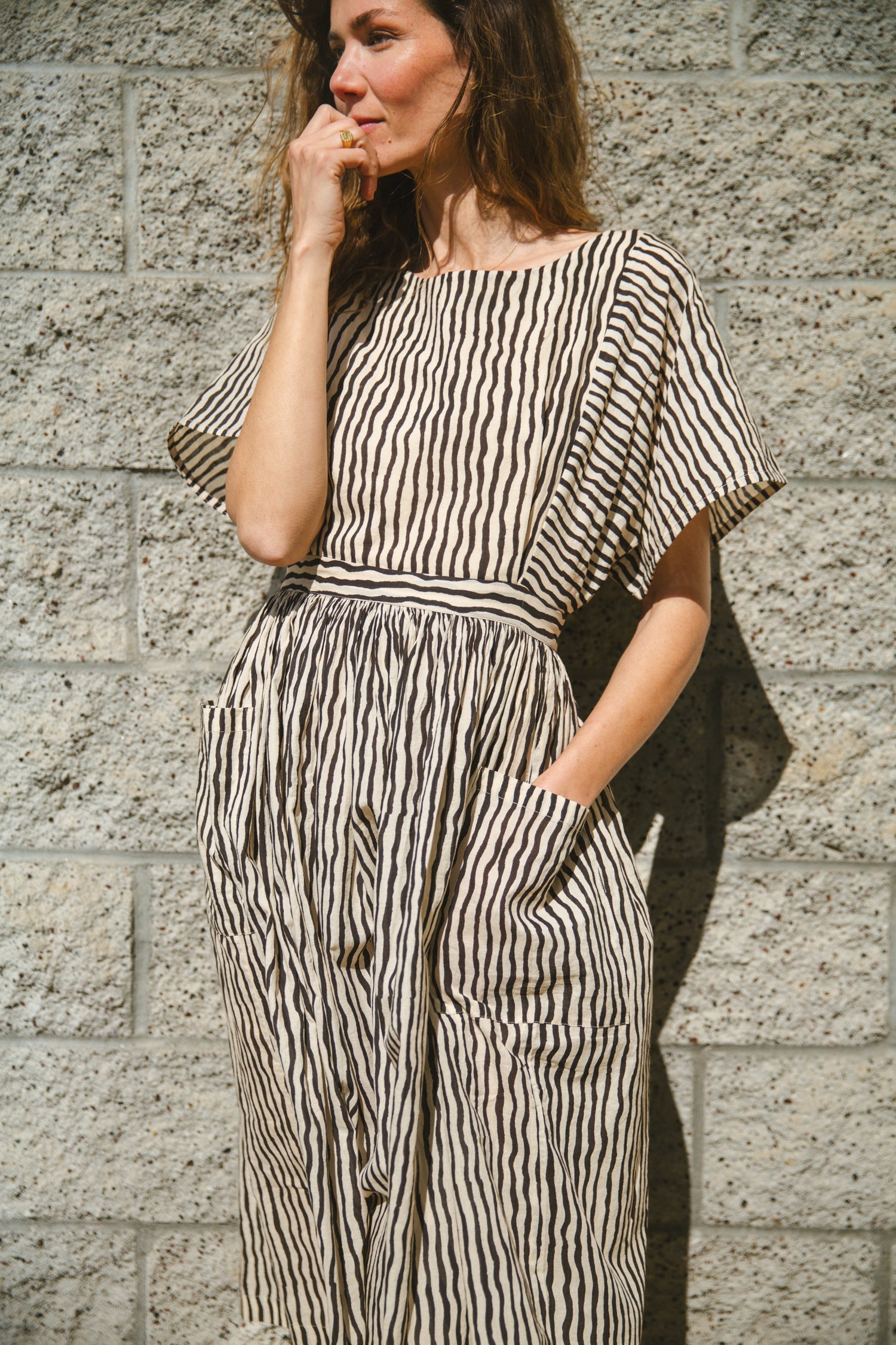 Black and white striped midi dress with short sleeves and an open-back design. Features a cinched waist with a tie detail for a flattering silhouette. Made from lightweight, breathable fabric, perfect for warm weather. A stylish choice for casual and semi-formal occasions.