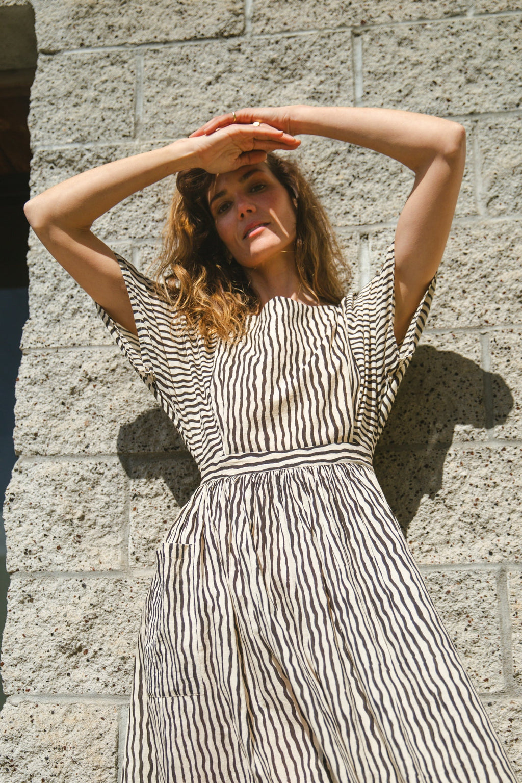 Black and white striped midi dress with short sleeves and an open-back design. Features a cinched waist with a tie detail for a flattering silhouette. Made from lightweight, breathable fabric, perfect for warm weather. A stylish choice for casual and semi-formal occasions.