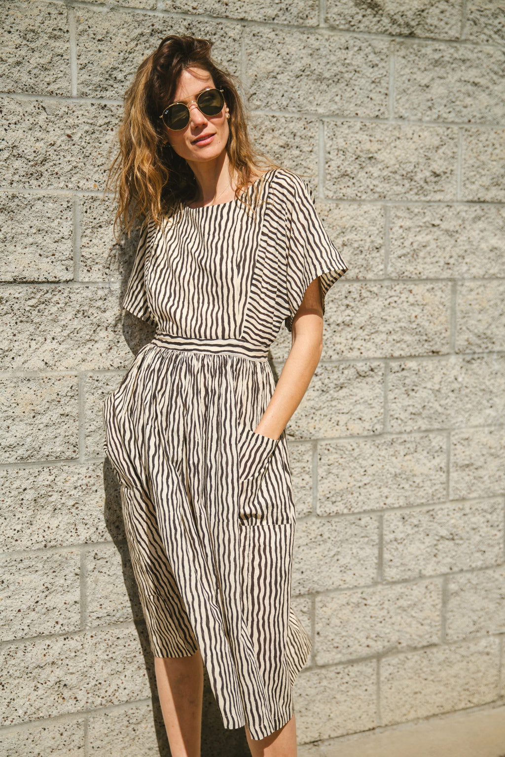 Black and white striped midi dress with short sleeves and an open-back design. Features a cinched waist with a tie detail for a flattering silhouette. Made from lightweight, breathable fabric, perfect for warm weather. A stylish choice for casual and semi-formal occasions.