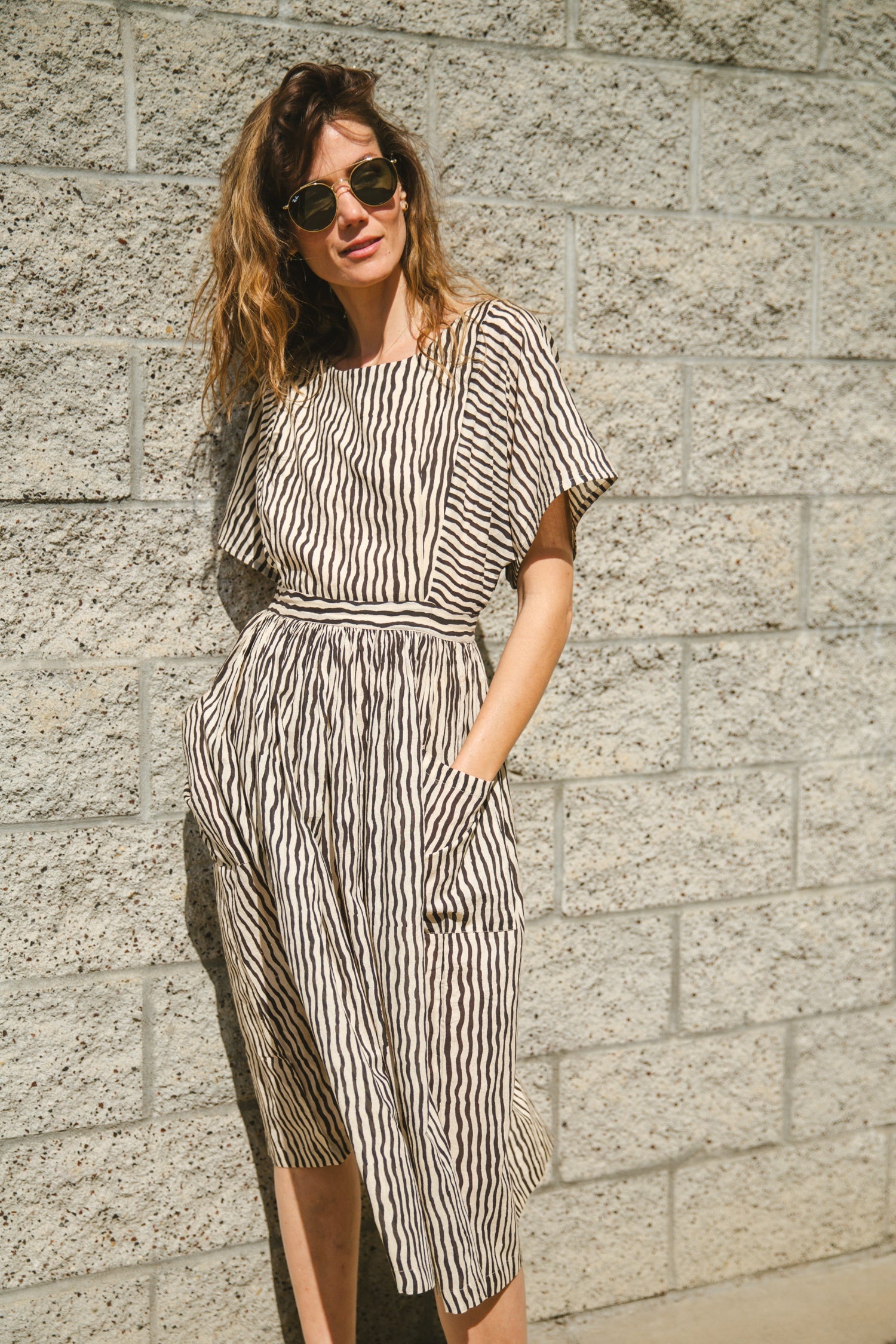Black and white striped midi dress with short sleeves and an open-back design. Features a cinched waist with a tie detail for a flattering silhouette. Made from lightweight, breathable fabric, perfect for warm weather. A stylish choice for casual and semi-formal occasions.