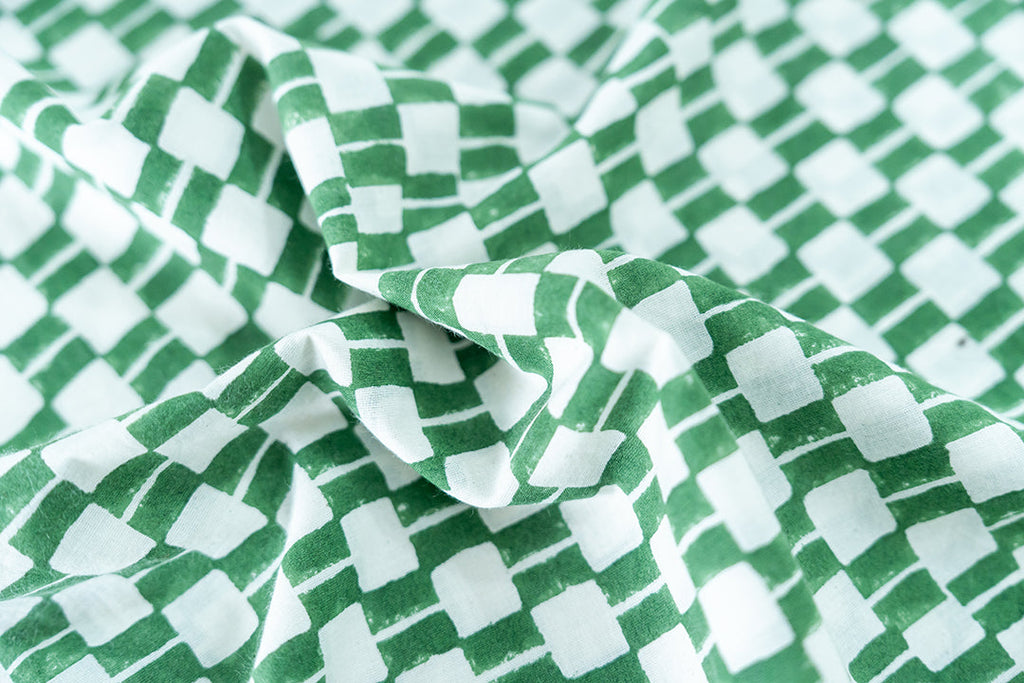 Green and white hand block-printed dress made from 100% organic cotton, featuring a front button opening and high-low hemline. Crafted over 5 days using azo-free dyes, the lightweight, non-stretchy fabric feels soft and breathable on the skin. Each piece is ethically made and uniquely one-of-a-kind, with subtle variations in print and color that highlight its artisanal nature. Falls 42” from the shoulder, offering a relaxed silhouette that fits true to size.