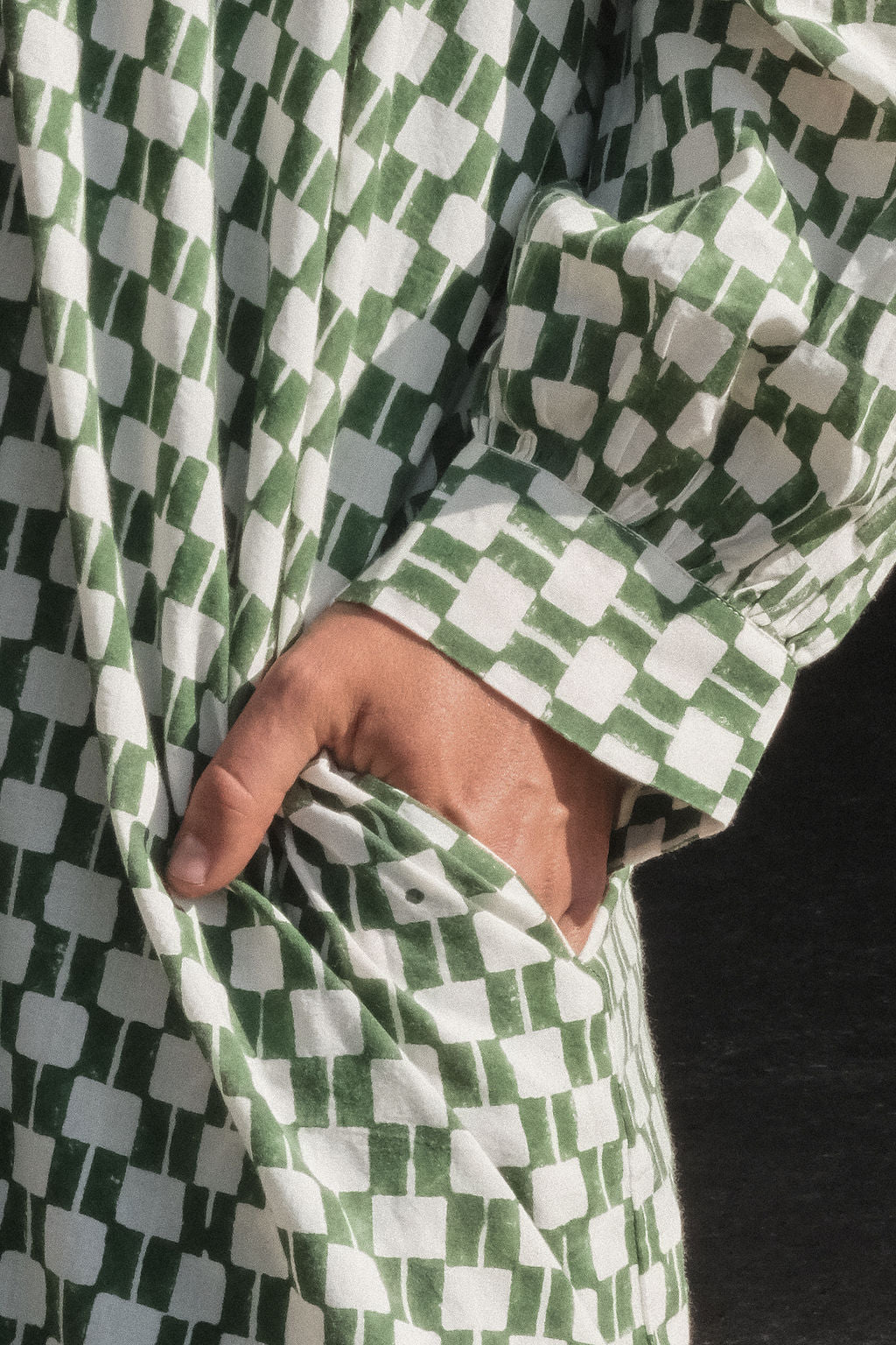 Green and white hand block-printed dress made from 100% organic cotton, featuring a front button opening and high-low hemline. Crafted over 5 days using azo-free dyes, the lightweight, non-stretchy fabric feels soft and breathable on the skin. Each piece is ethically made and uniquely one-of-a-kind, with subtle variations in print and color that highlight its artisanal nature. Falls 42” from the shoulder, offering a relaxed silhouette that fits true to size.