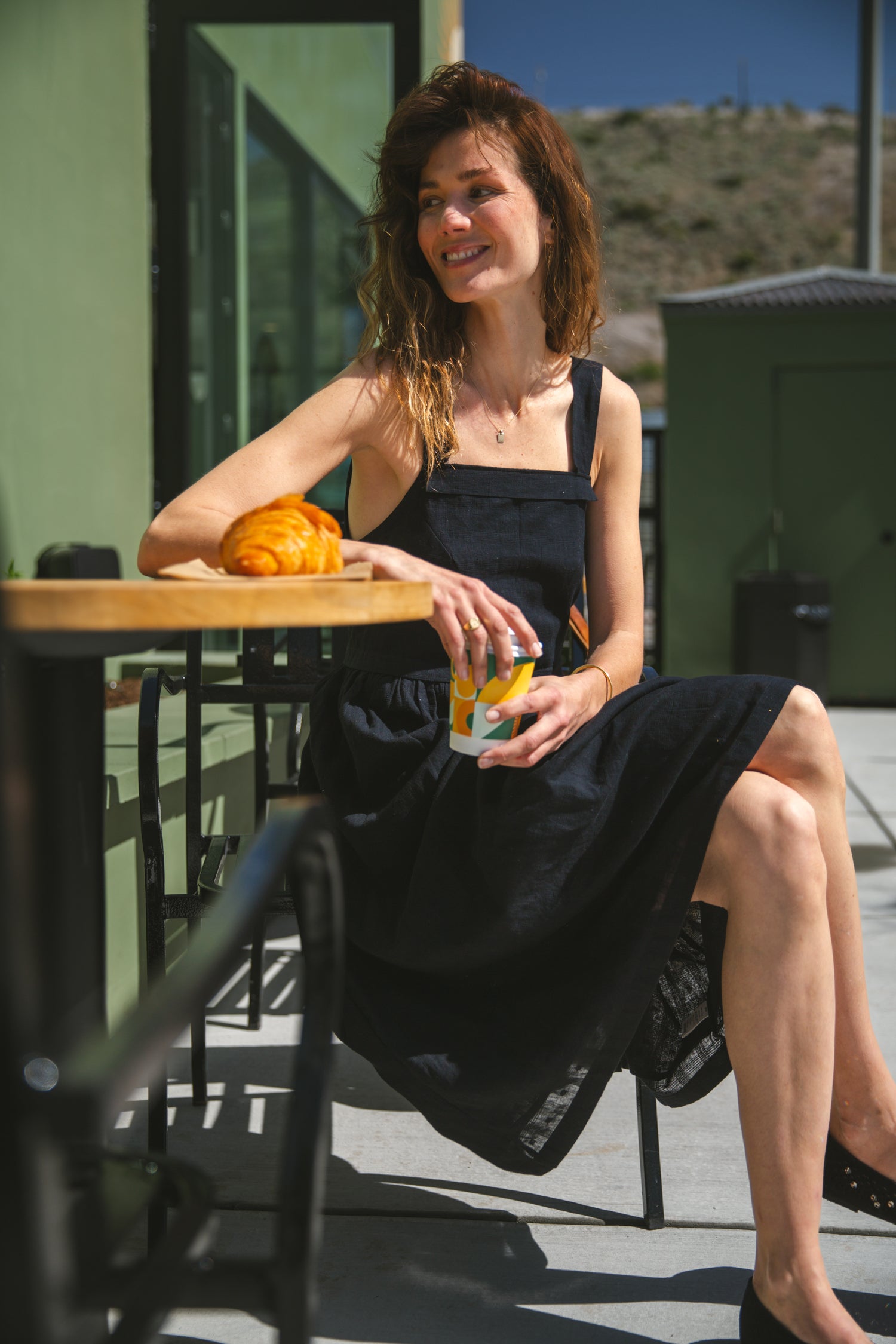 This is a black sleeveless midi dress with a structured square neckline and wide shoulder straps. The dress features a loose, flowing silhouette with a gathered waistline that adds volume and movement. Crafted from a lightweight, breathable fabric, it drapes effortlessly, making it perfect for warm weather. Functional side pockets enhance its practicality, while the relaxed fit exudes a laid-back yet refined charm. The minimalist design and deep black hue create a versatile piece that can be styled casually