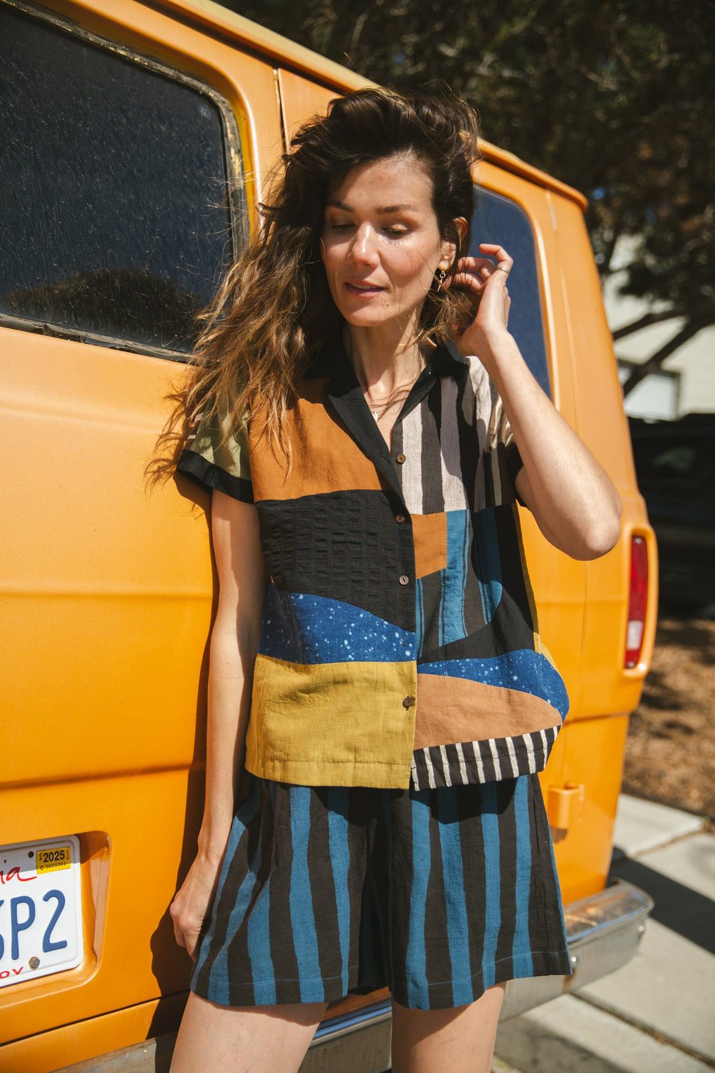 Color-blocked patchwork short-sleeve shirt featuring bold striped and solid fabric panels in earthy tones. Designed with a relaxed fit, button-down front, and a sharp collar for a modern, eclectic look.