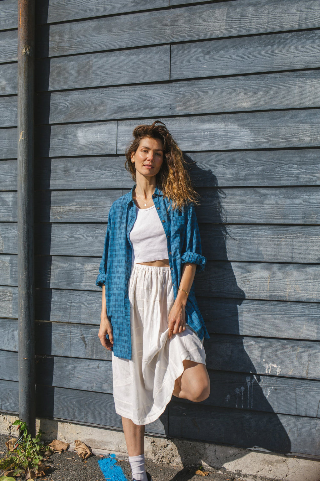 White flowy midi skirt with subtle plaid pattern, lightweight fabric, and gathered waist for an elegant and casual look.