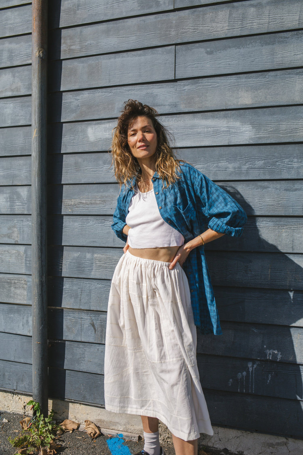 White flowy midi skirt with subtle plaid pattern, lightweight fabric, and gathered waist for an elegant and casual look.