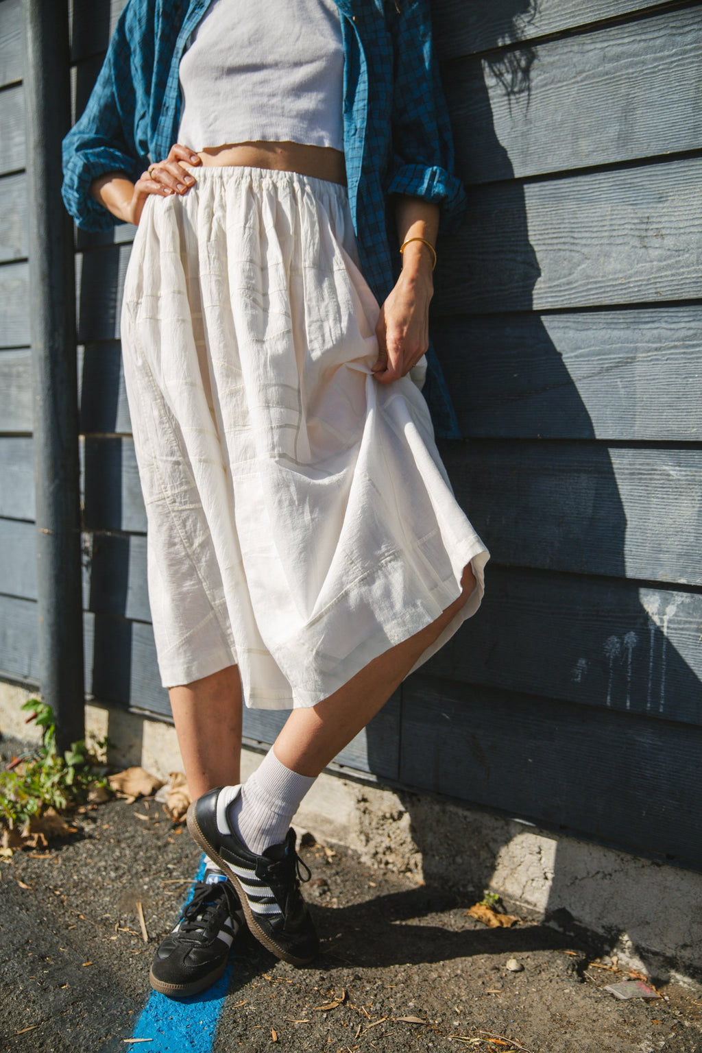 White flowy midi skirt with subtle plaid pattern, lightweight fabric, and gathered waist for an elegant and casual look.
