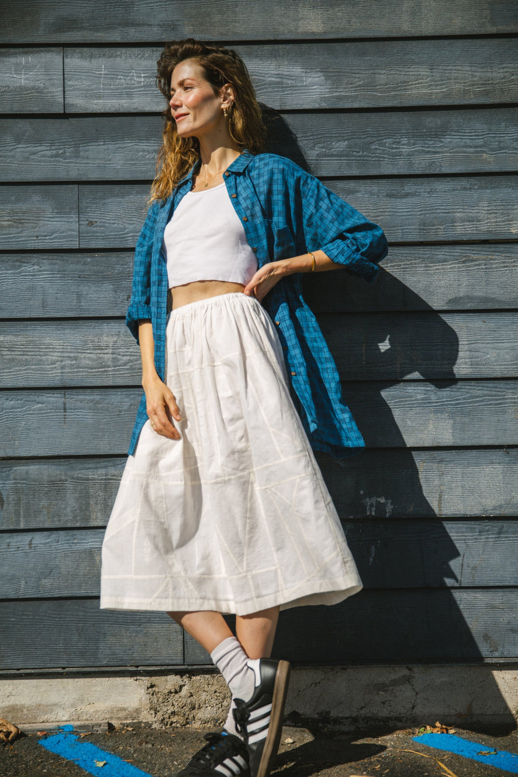 White flowy midi skirt with subtle plaid pattern, lightweight fabric, and gathered waist for an elegant and casual look.