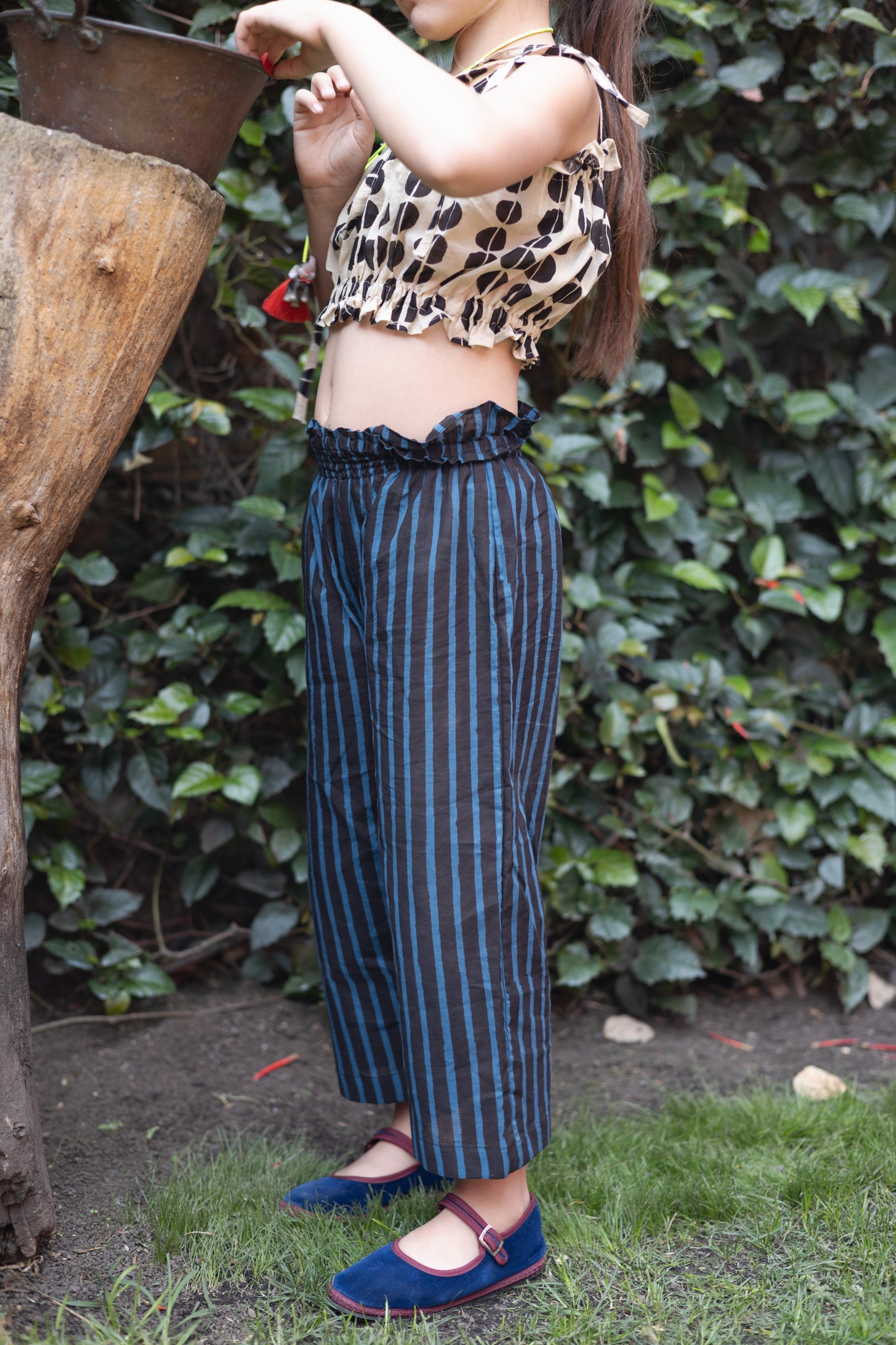 A pair of kids' wide-leg pants featuring vertical blue and black stripes. The pants have a high, elasticated waistband for a comfortable fit and a slightly cropped length, adding a relaxed and playful touch to the outfit.