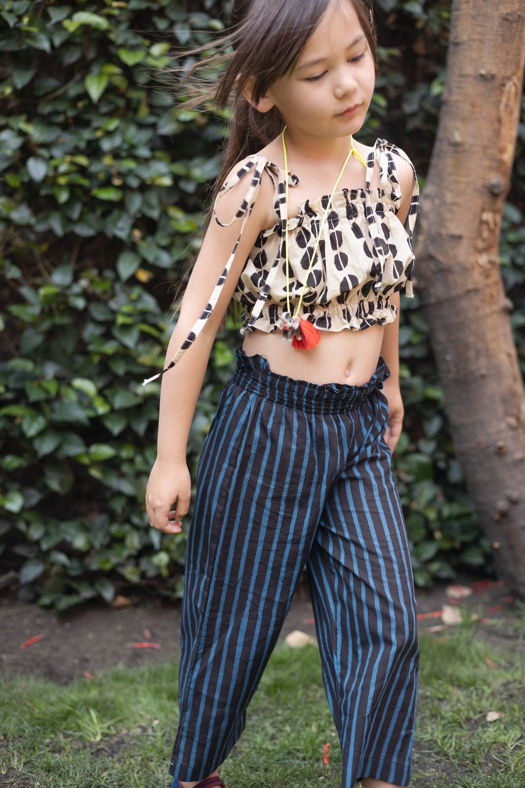 A pair of kids' wide-leg pants featuring vertical blue and black stripes. The pants have a high, elasticated waistband for a comfortable fit and a slightly cropped length, adding a relaxed and playful touch to the outfit.