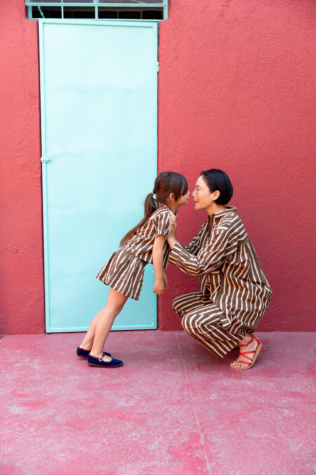 A pair of brown and white vertically striped kids' shorts with a loose, relaxed fit. The shorts have an elastic waistband for comfort and a slightly flared silhouette, styled as part of a matching set with a collared short-sleeve shirt.
