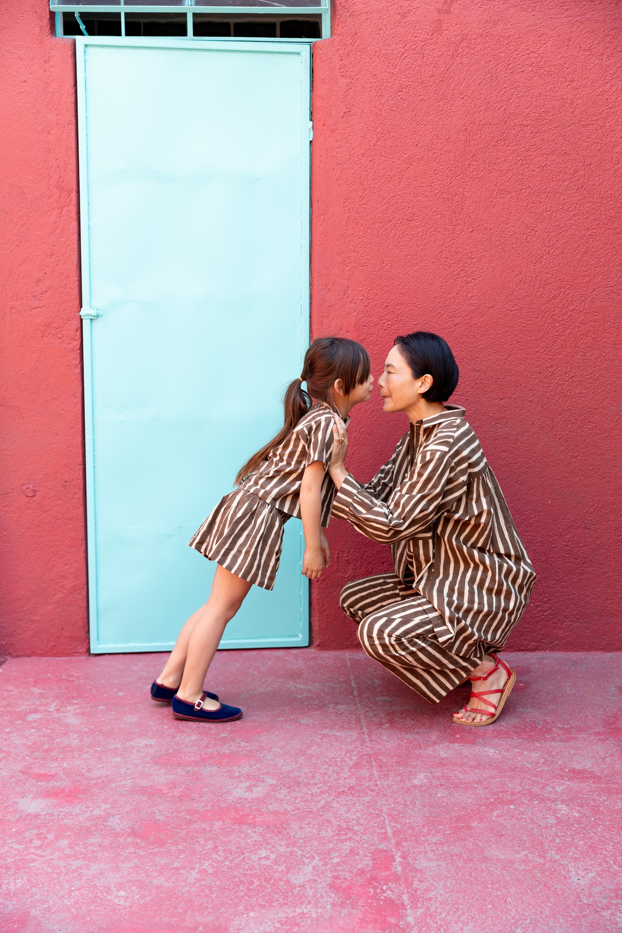 A pair of brown and white vertically striped kids' shorts with a loose, relaxed fit. The shorts have an elastic waistband for comfort and a slightly flared silhouette, styled as part of a matching set with a collared short-sleeve shirt.