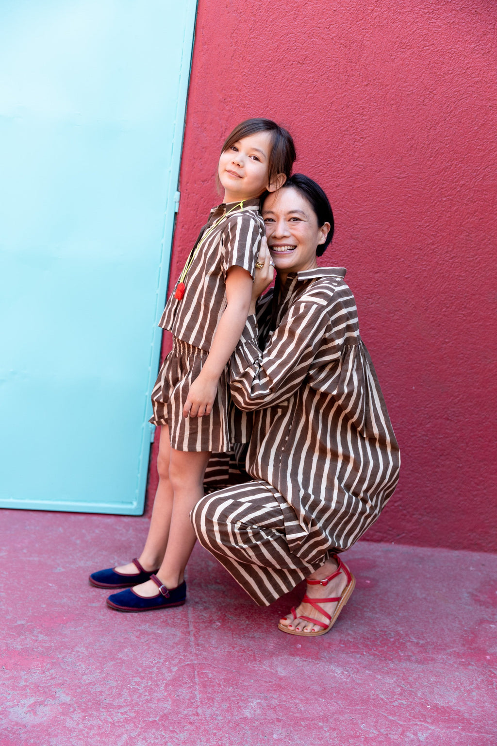 A pair of brown and white vertically striped kids' shorts with a loose, relaxed fit. The shorts have an elastic waistband for comfort and a slightly flared silhouette, styled as part of a matching set with a collared short-sleeve shirt.