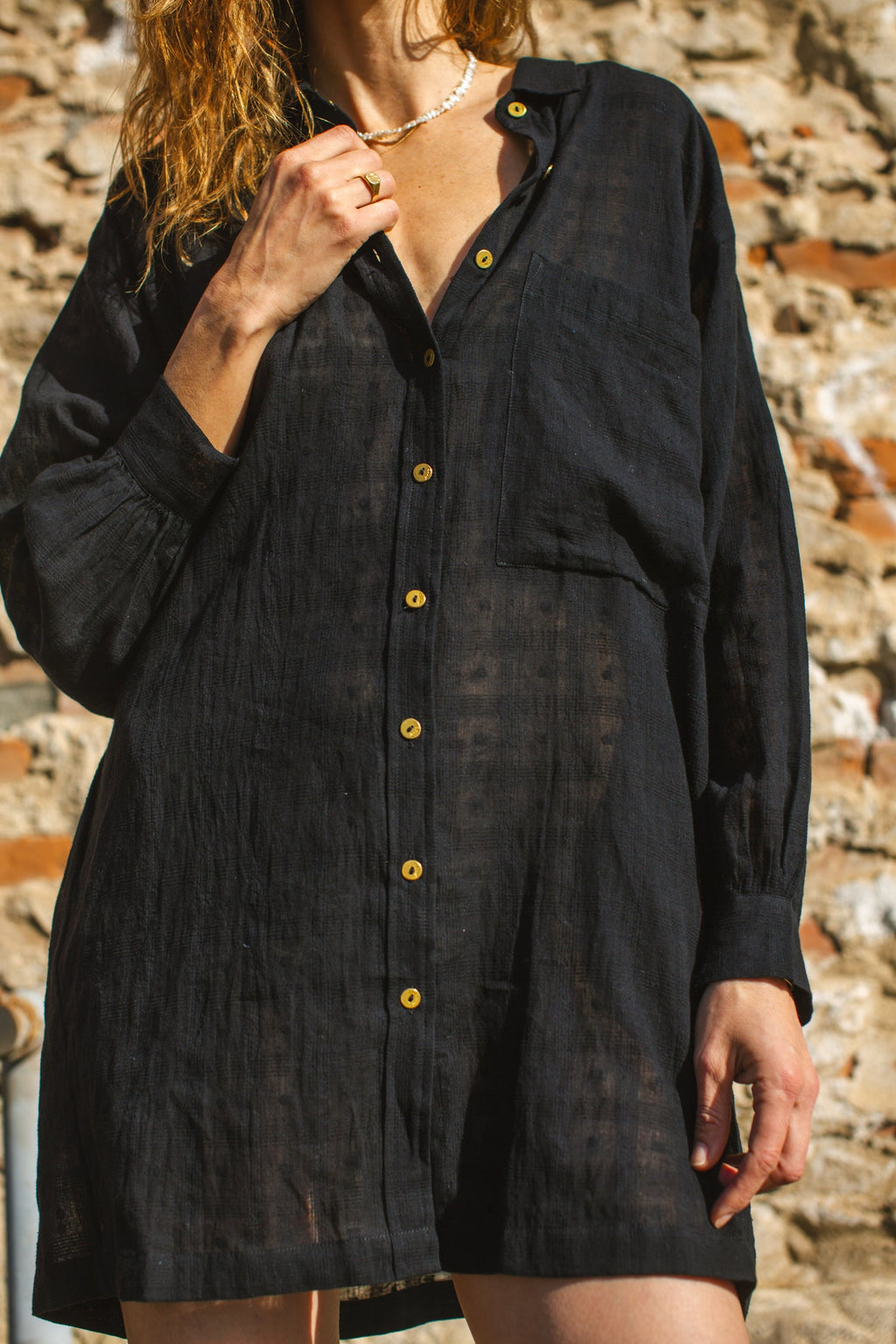 Black artist smock with a relaxed, oversized fit, featuring a button-down front, billowy long sleeves with gathered cuffs, and a subtle textured fabric. The lightweight, breathable material drapes effortlessly, creating a casual yet artistic look.