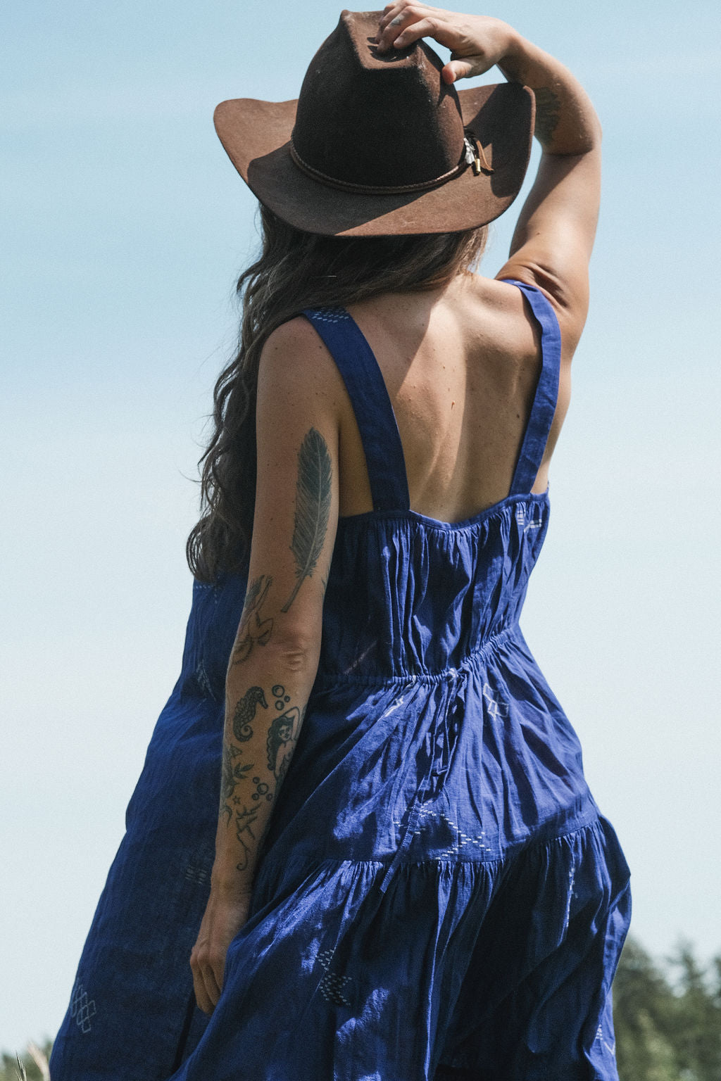 Long indigo blue Jamdani dress featuring wide straps, a gathered neckline, and subtle white abstract geometric motifs. Handwoven from soft, lightweight cotton and dyed with azo-free dyes, this fully lined dress is crafted over 7 days using traditional weaving techniques. Ethically made with a relaxed, bohemian silhouette, it's perfect for summer wear—combining artisanal charm with breathable comfort.