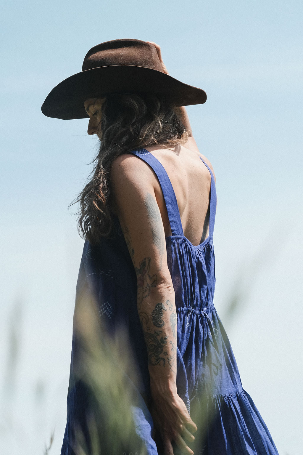 Long indigo blue Jamdani dress featuring wide straps, a gathered neckline, and subtle white abstract geometric motifs. Handwoven from soft, lightweight cotton and dyed with azo-free dyes, this fully lined dress is crafted over 7 days using traditional weaving techniques. Ethically made with a relaxed, bohemian silhouette, it's perfect for summer wear—combining artisanal charm with breathable comfort.