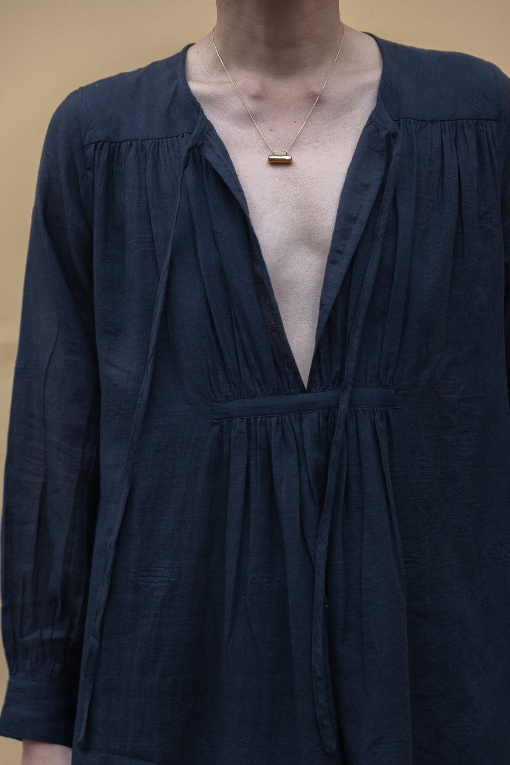 Black midi dress with long sleeves, a deep V-neckline with delicate gathers, and adjustable tie details. Designed with a relaxed waist and flowy fabric for effortless movement.