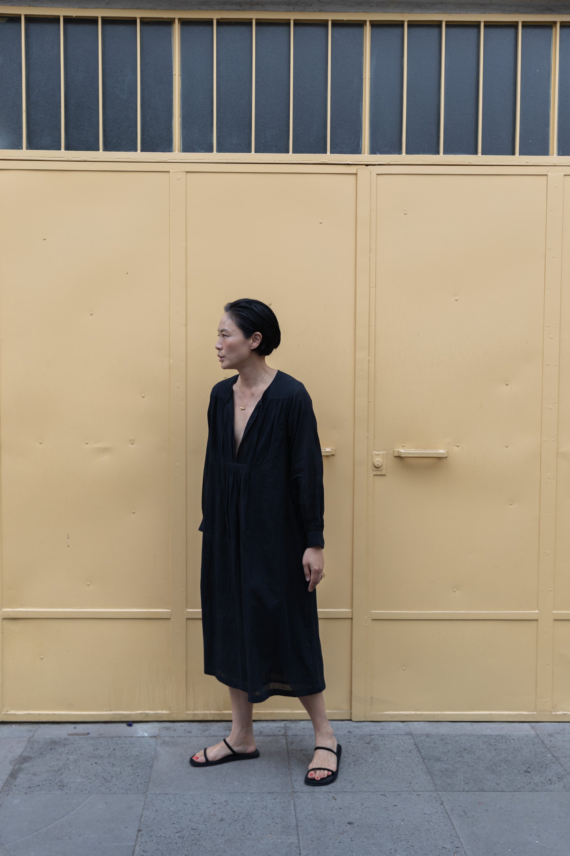 Black midi dress with long sleeves, a deep V-neckline with delicate gathers, and adjustable tie details. Designed with a relaxed waist and flowy fabric for effortless movement.