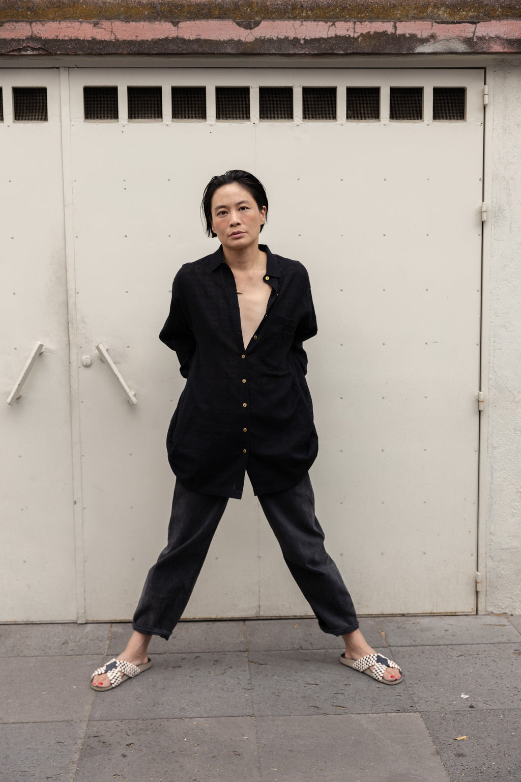Black artist smock with a relaxed, oversized fit, featuring a button-down front, billowy long sleeves with gathered cuffs, and a subtle textured fabric. The lightweight, breathable material drapes effortlessly, creating a casual yet artistic look.
