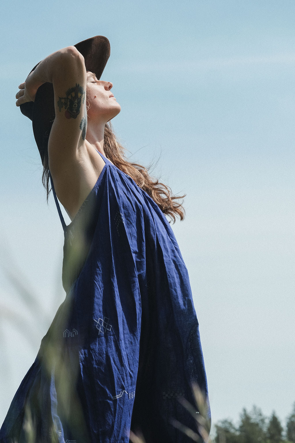 Long indigo blue Jamdani dress featuring wide straps, a gathered neckline, and subtle white abstract geometric motifs. Handwoven from soft, lightweight cotton and dyed with azo-free dyes, this fully lined dress is crafted over 7 days using traditional weaving techniques. Ethically made with a relaxed, bohemian silhouette, it's perfect for summer wear—combining artisanal charm with breathable comfort.